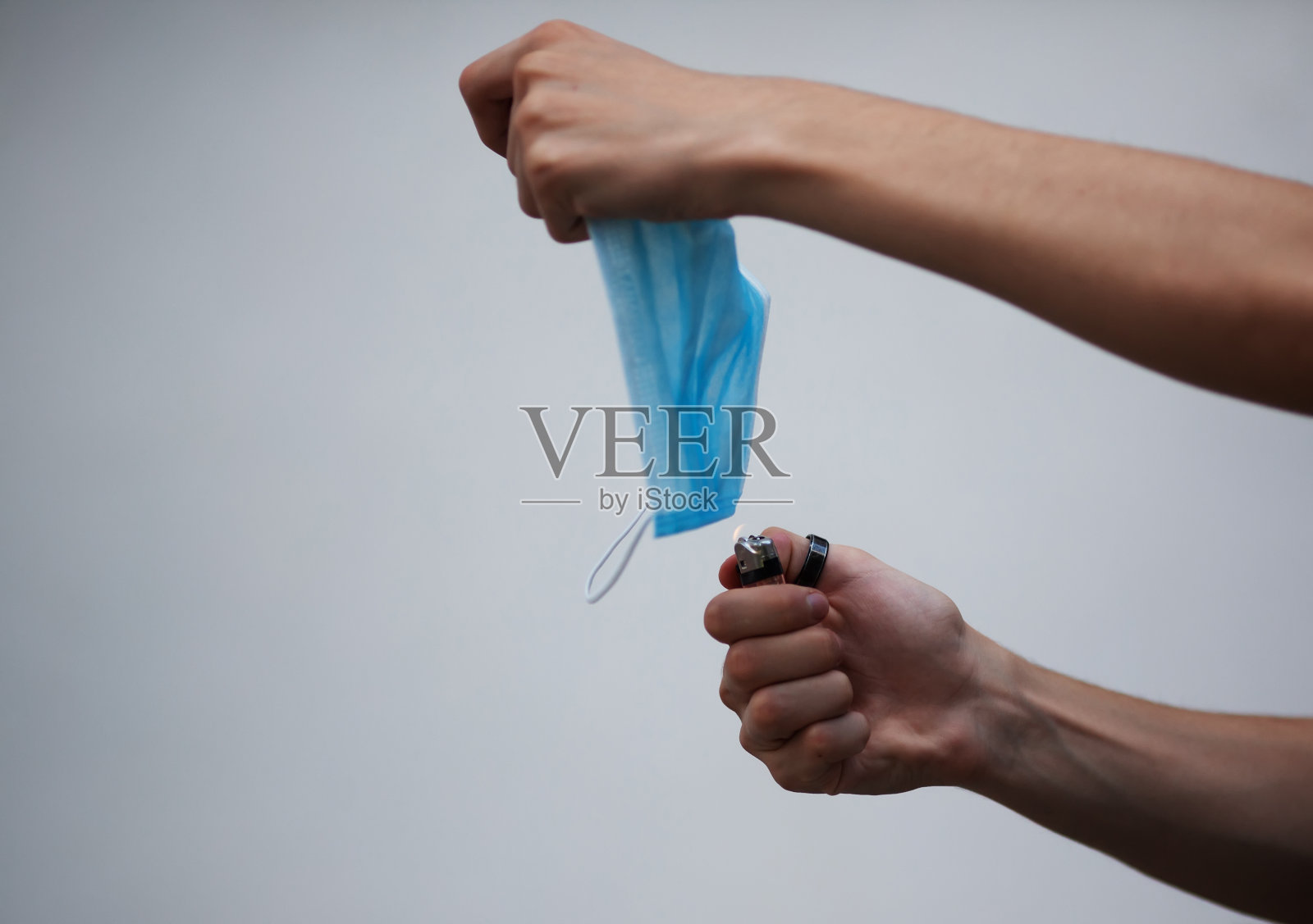手拿打火机点燃医用口罩照片摄影图片