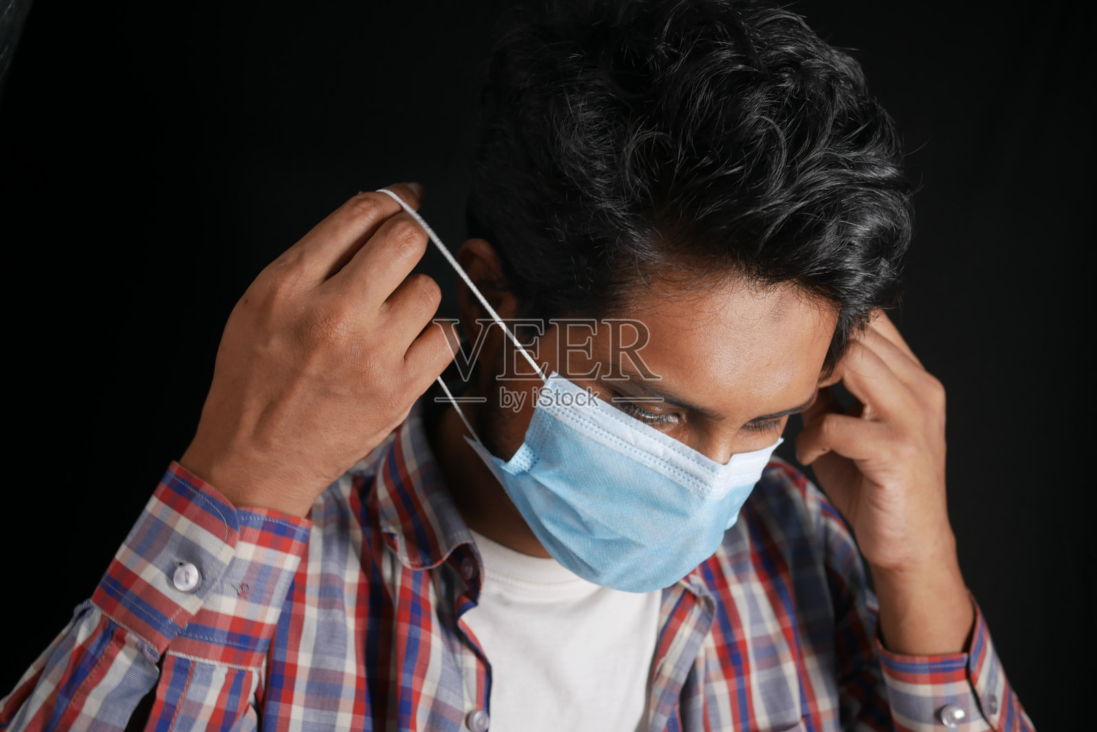 年轻的亚洲男子把外科口罩放在室内照片摄影图片