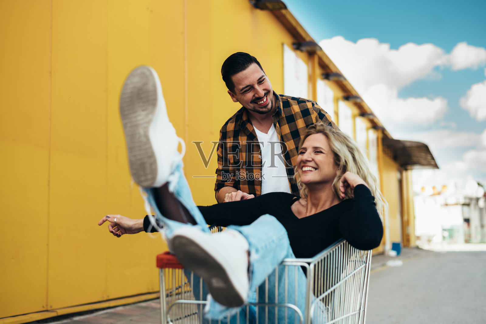 近景:一对幸福的年轻夫妇坐在购物车里玩得很开心照片摄影图片