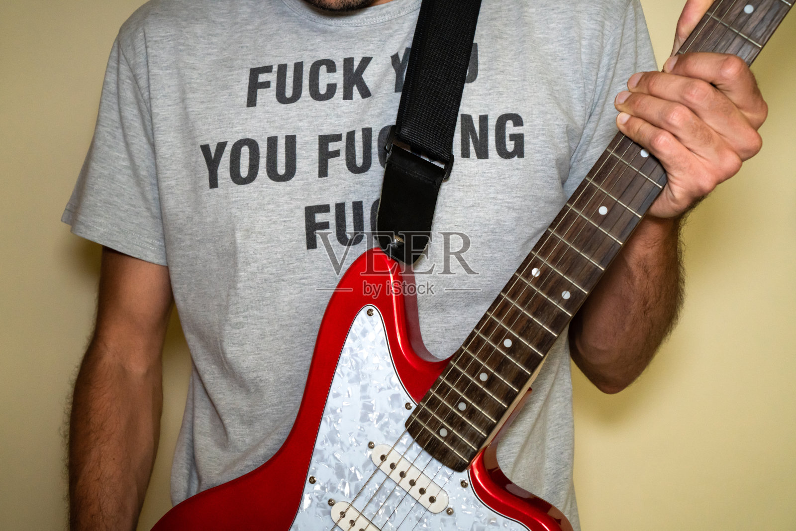 一个年轻人穿着一件冒犯性的t恤,一边弹电吉他照片摄影图片