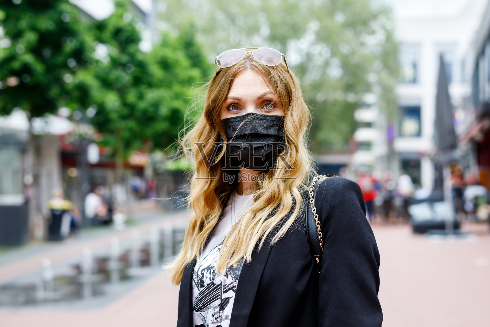 年轻美丽的女人戴着医用口罩,以保护自己免受冠状病毒的侵害。欧洲和世界的新冠疫情时间。安全的人。夏日之城的女人。照片摄影图片