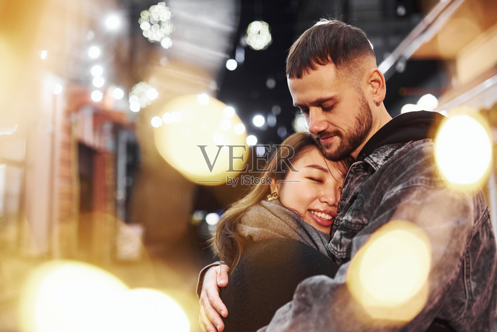 互相拥抱。幸福的多种族夫妇一起在城市户外庆祝新年照片摄影图片