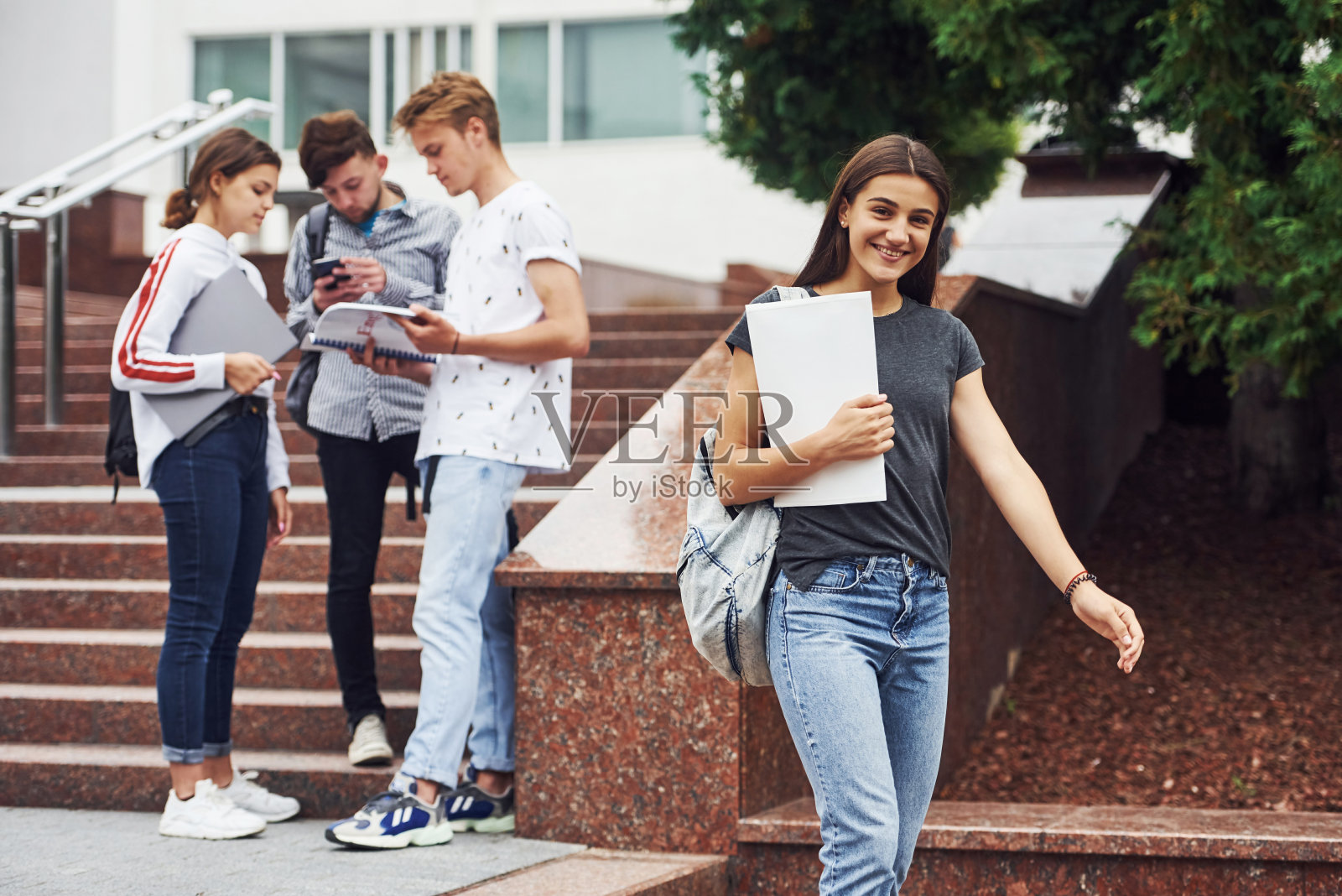 积极向上的女孩在朋友面前。白天在大学附近的一群穿着便服的年轻学生照片摄影图片