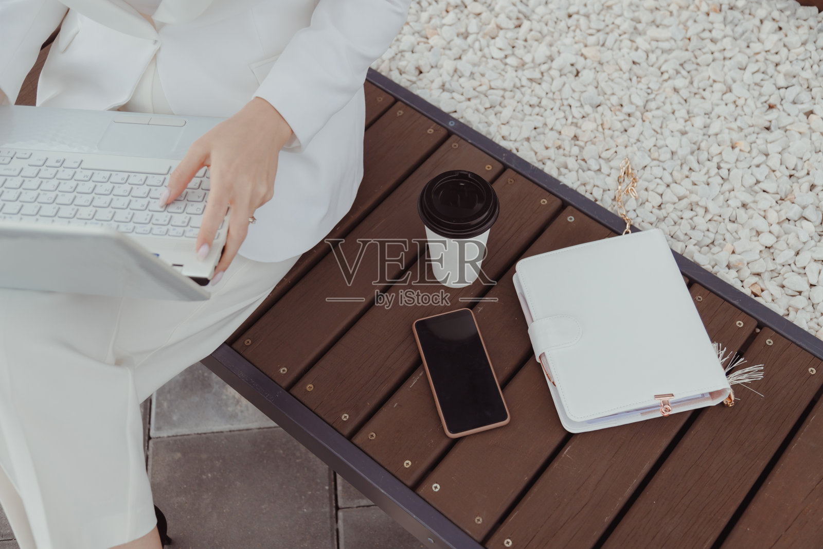 俯视图女性工作在笔记本电脑,智能手机,一杯咖啡。白色女性风格风格。照片摄影图片