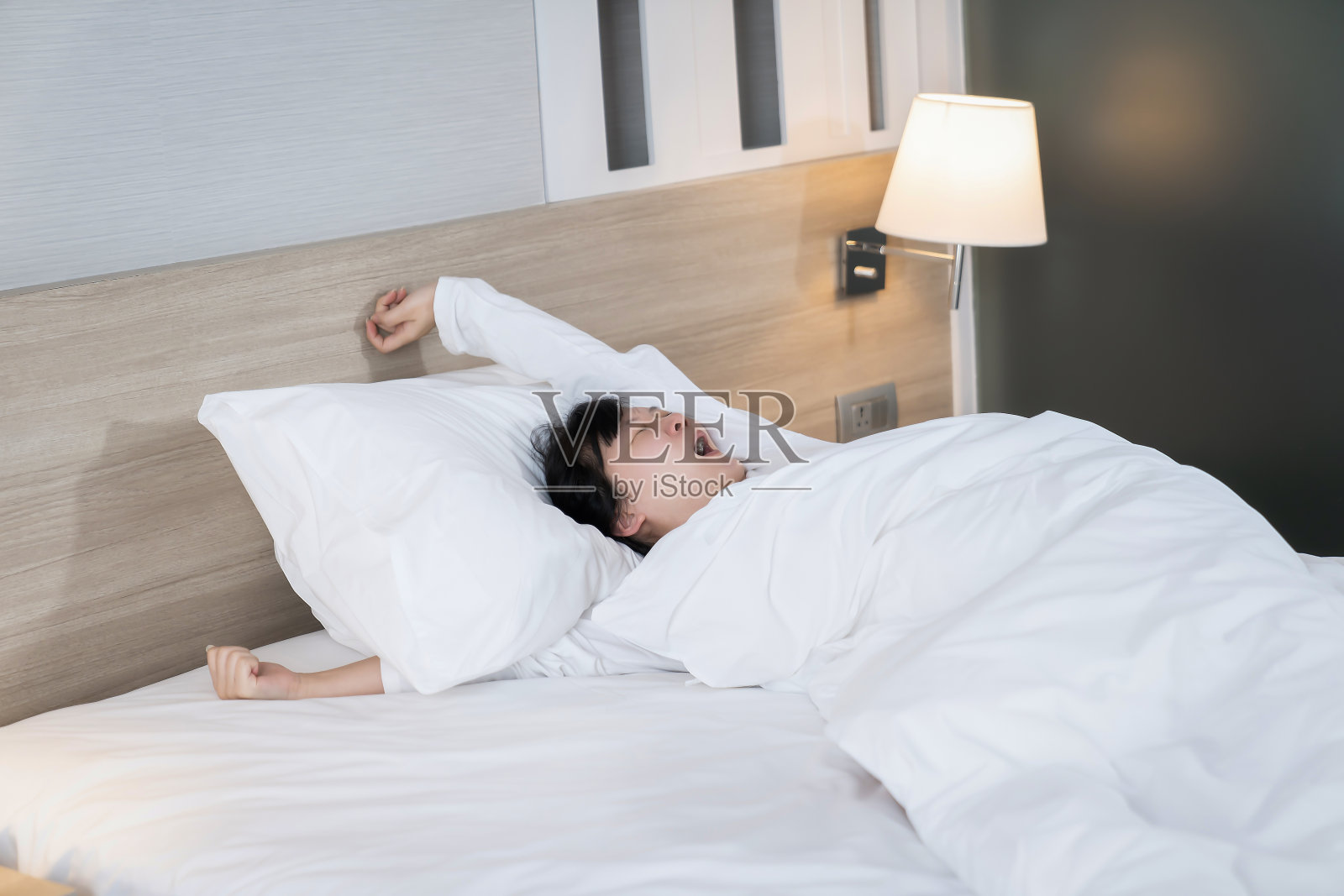 亚洲女性早上起床后正在打哈欠和伸展身体。照片摄影图片