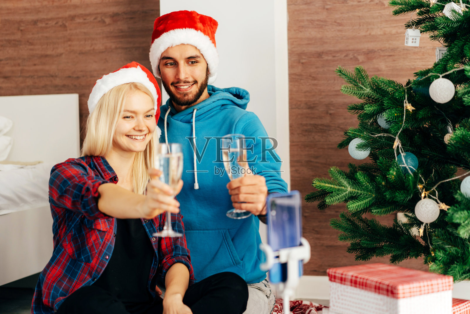 年轻男女端着香槟,通过手机上的视频交流向朋友祝贺照片摄影图片