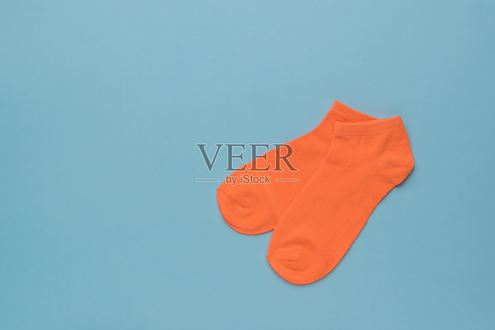 蓝色背景下的橙色运动袜。平的。照片摄影图片