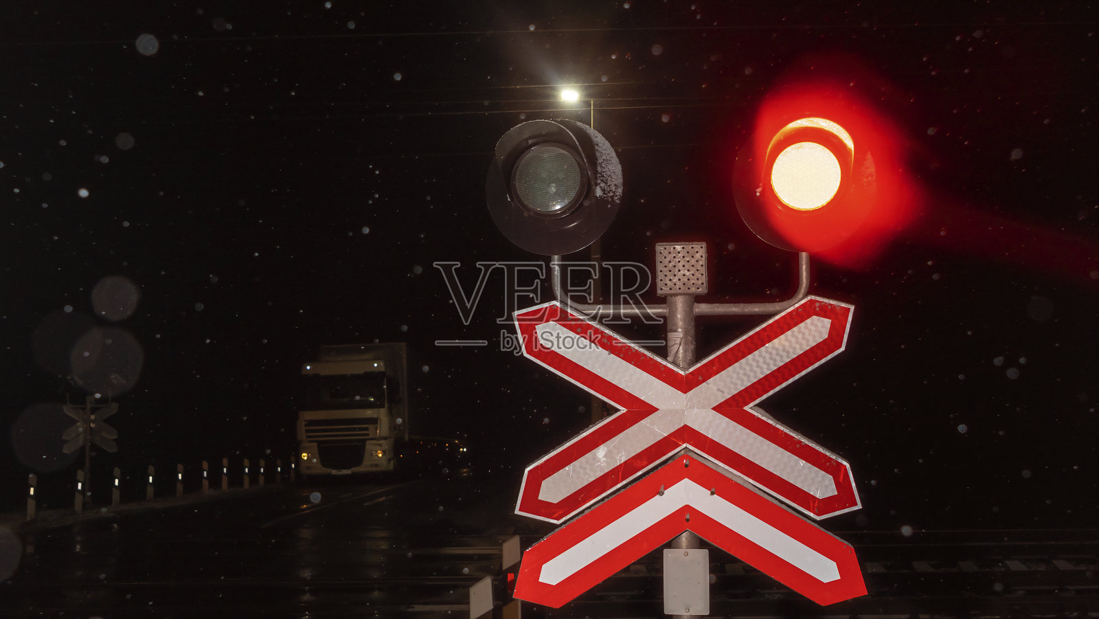 火车道口的大门在夜间关闭。火车通过时,车灯闪烁或闪烁。安全的概念。照片摄影图片