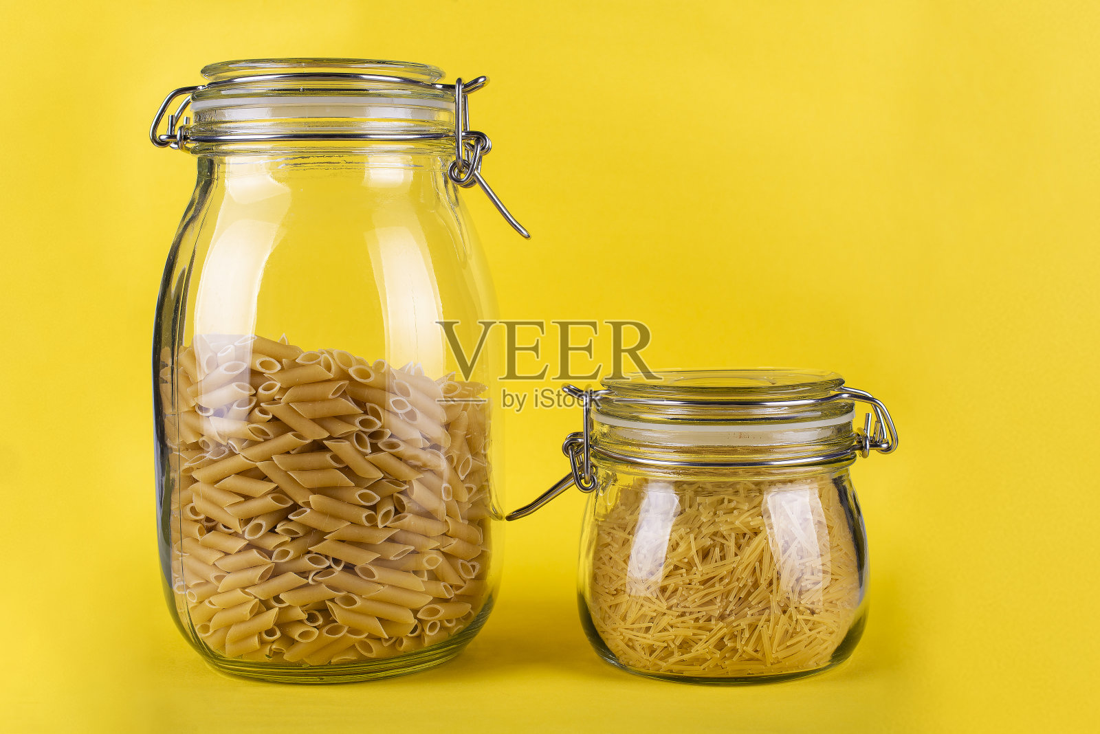黄色背景下的玻璃罐里的意大利面被隔离照片摄影图片