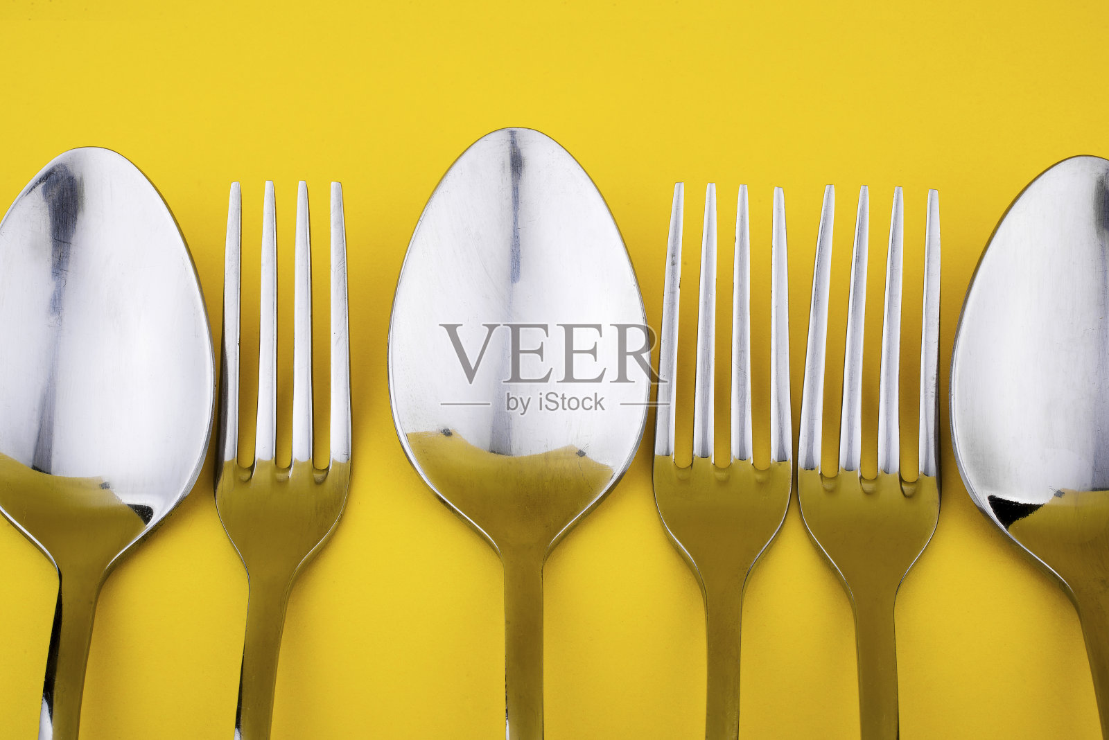 在黄色背景上的一套餐具的特写和选择性聚焦。平躺和俯视图的勺子,叉子和刀与复制空间。厨房食品设备。照片摄影图片