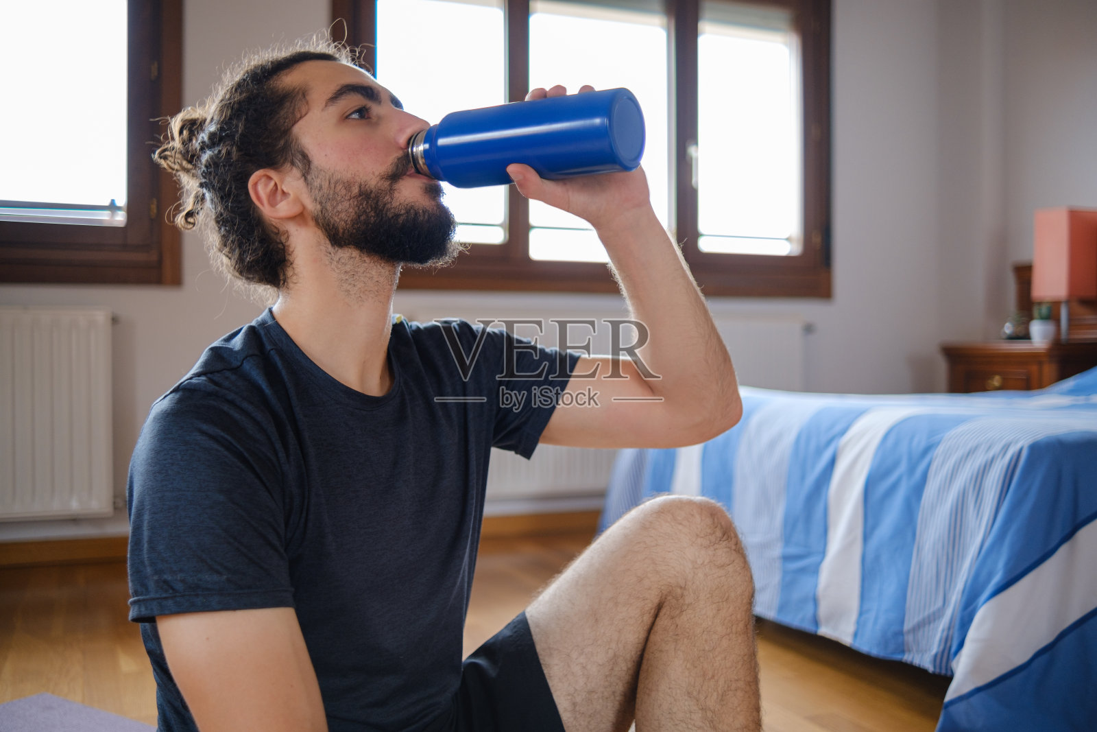 大胡子男人的肖像,在家里喝水,锻炼休息。照片摄影图片
