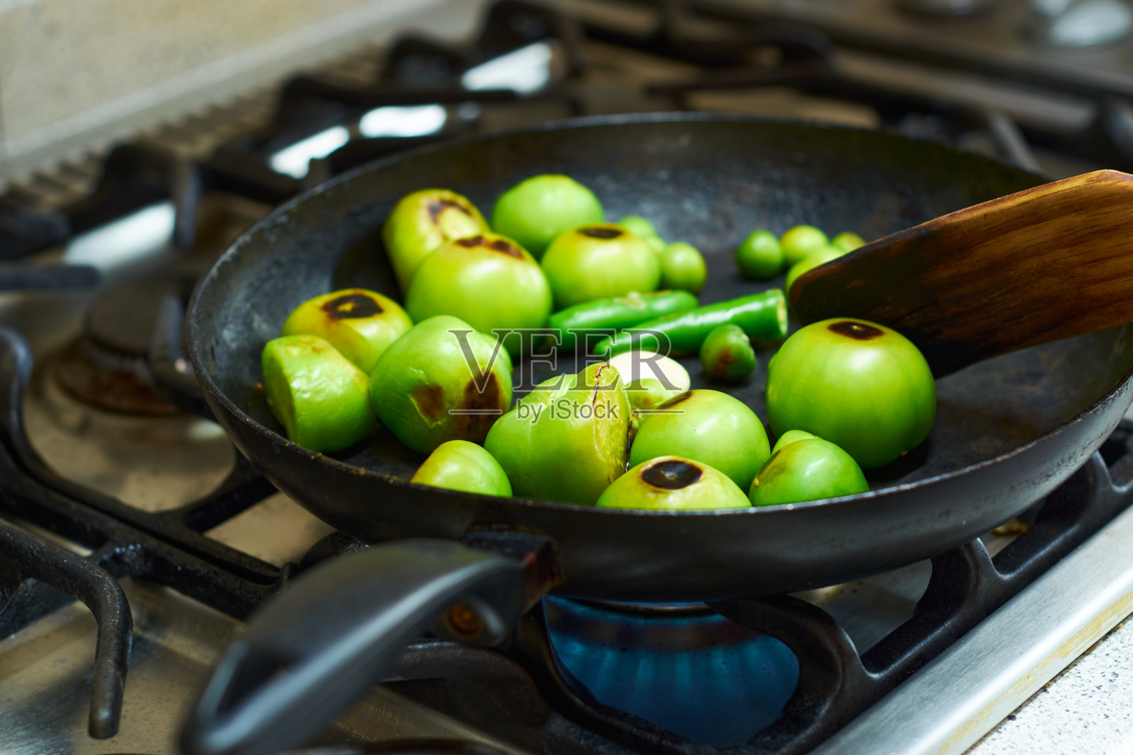 把绿色的西红柿放在烤炉上烤,自制酱汁。照片摄影图片