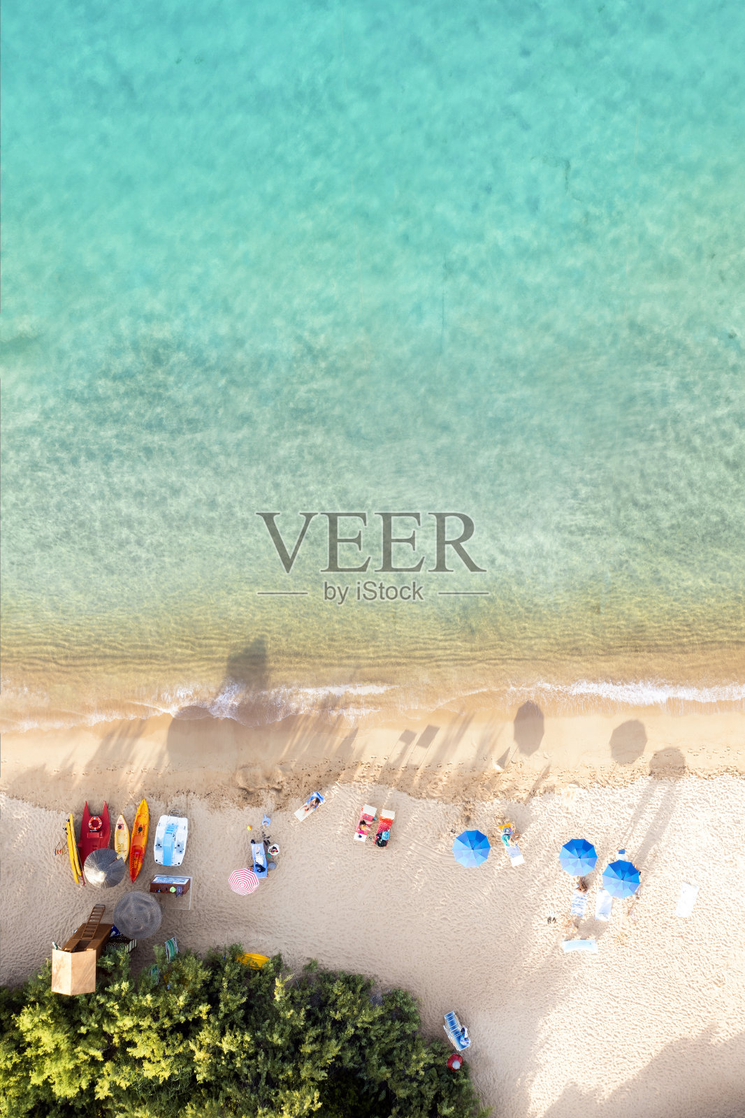 从上面看,令人惊叹的鸟瞰图,白色的沙滩沐浴在蓝绿色的水和放松的人们在一些沙滩伞下日落。卡拉迪沃尔普海滩,Costa meralda,撒丁岛,意大利。照片摄影图片