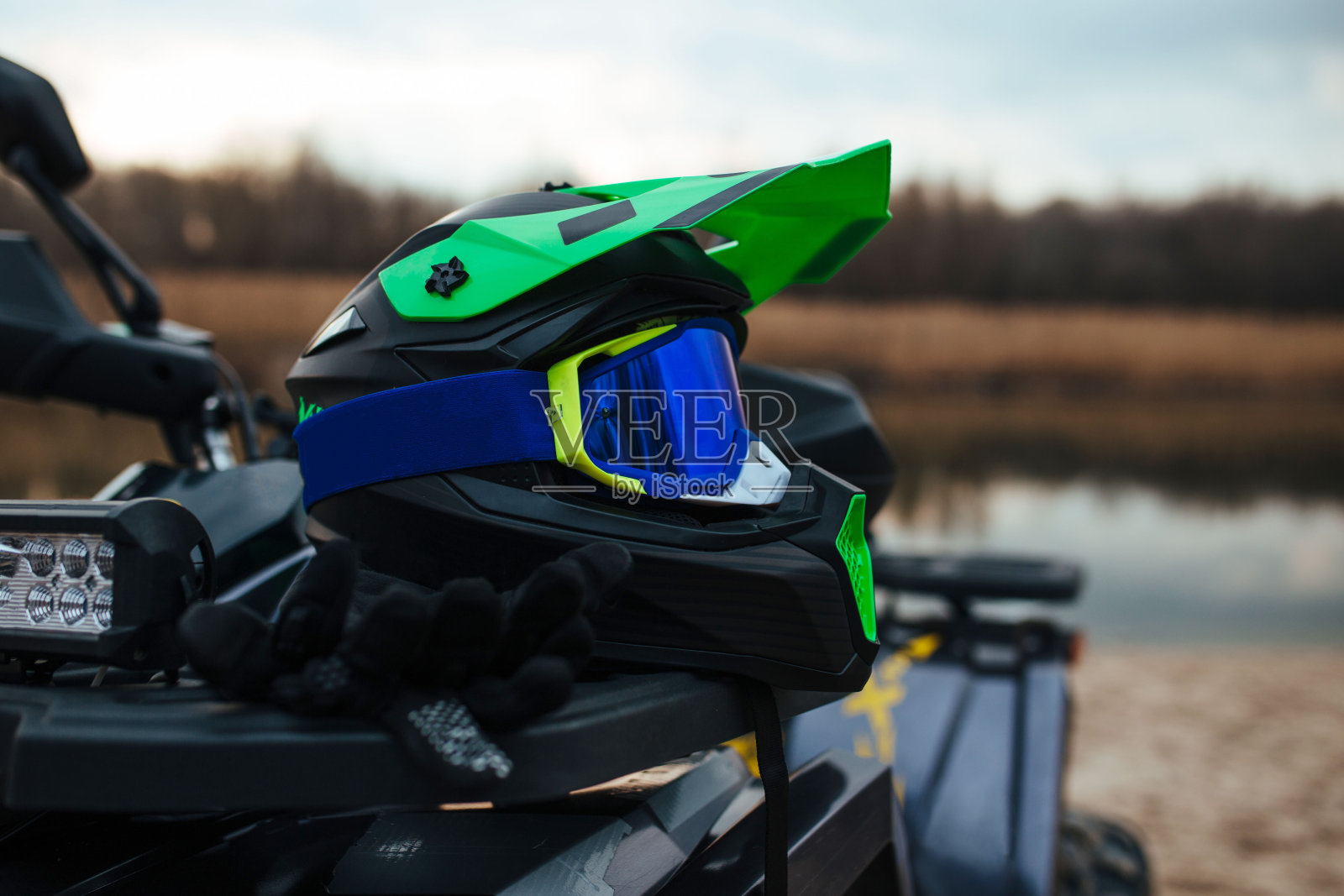 一个耐磨的绿色亚视头盔在河流和沙子的背景。照片摄影图片