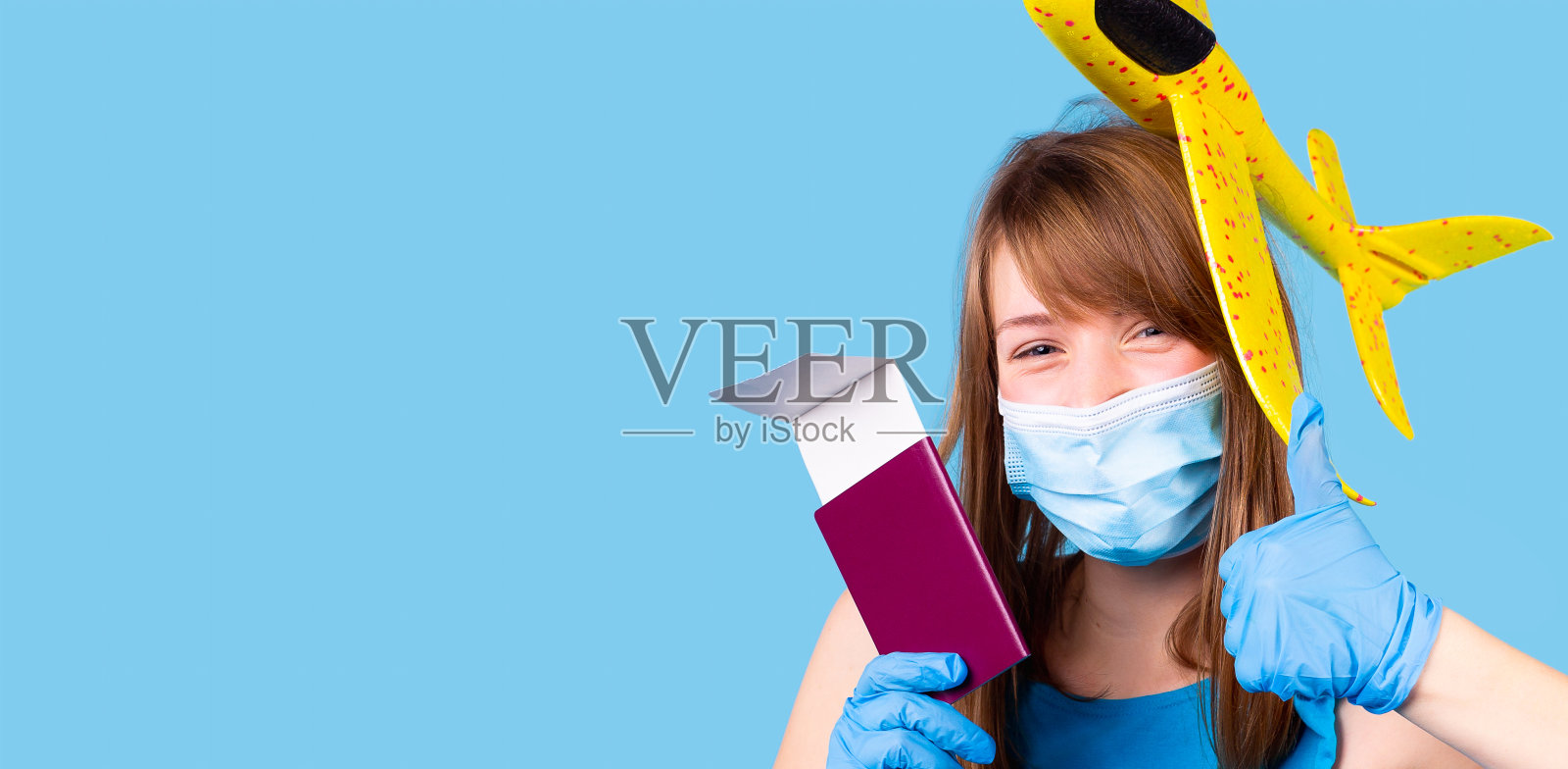 戴着医用口罩和手套的快乐女人,带着微笑的眼睛,手里拿着护照和在疫情期间旅行的机票。照片摄影图片