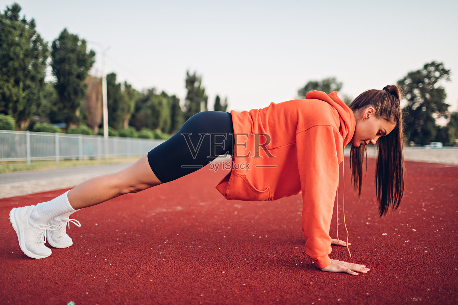 一名年轻女子清晨在操场上做热身运动照片摄影图片