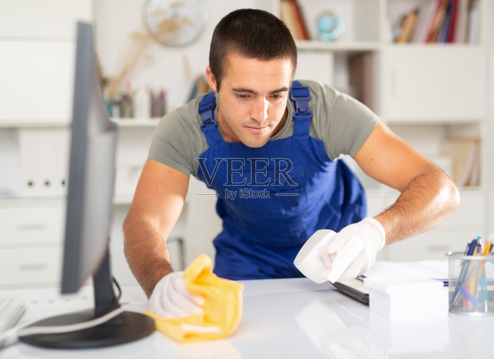 清洁工人用清洁剂擦拭办公桌照片摄影图片