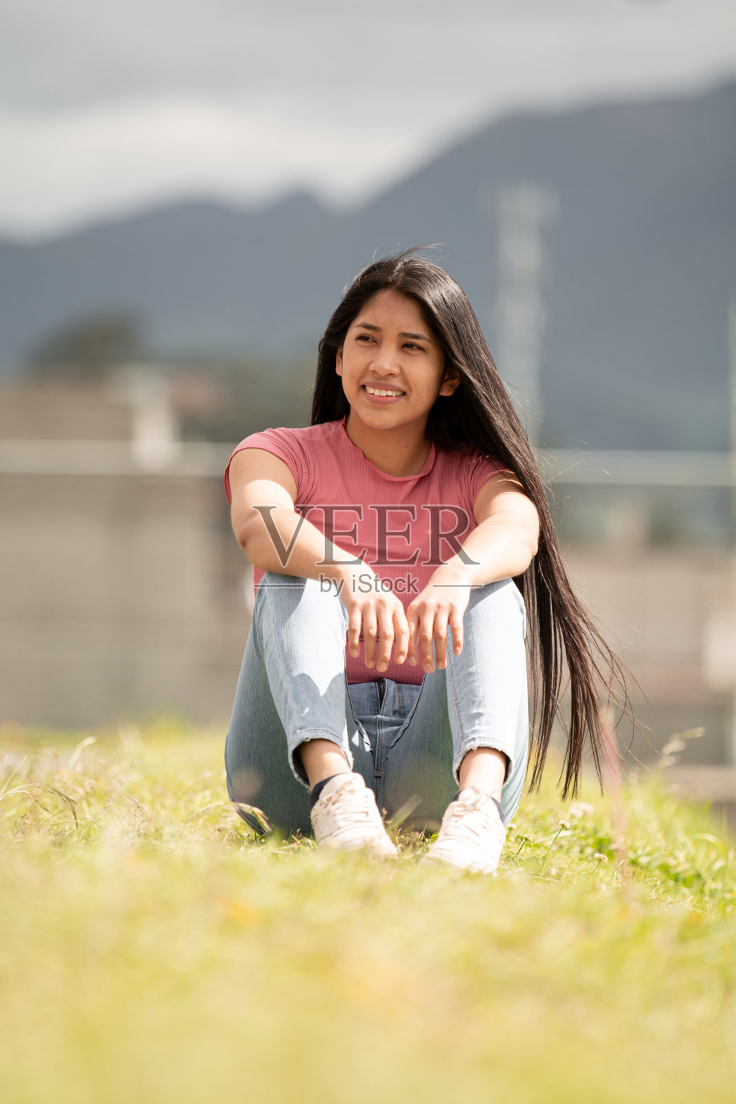 微笑的西班牙女孩坐在绿色的区域,自由的概念照片摄影图片