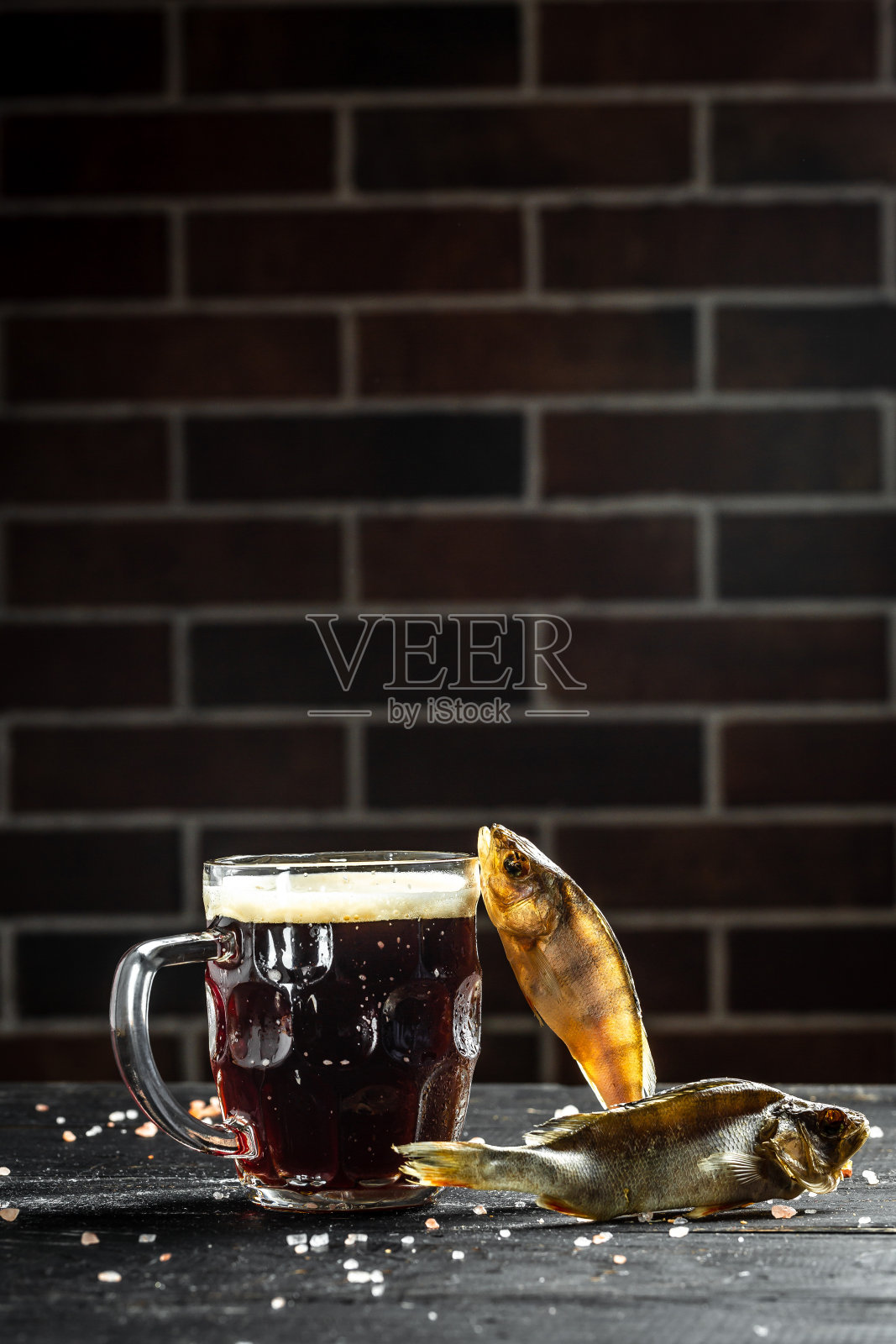 一杯啤酒和河鱼干。黑色背景。垂直的图像。文本的地方照片摄影图片