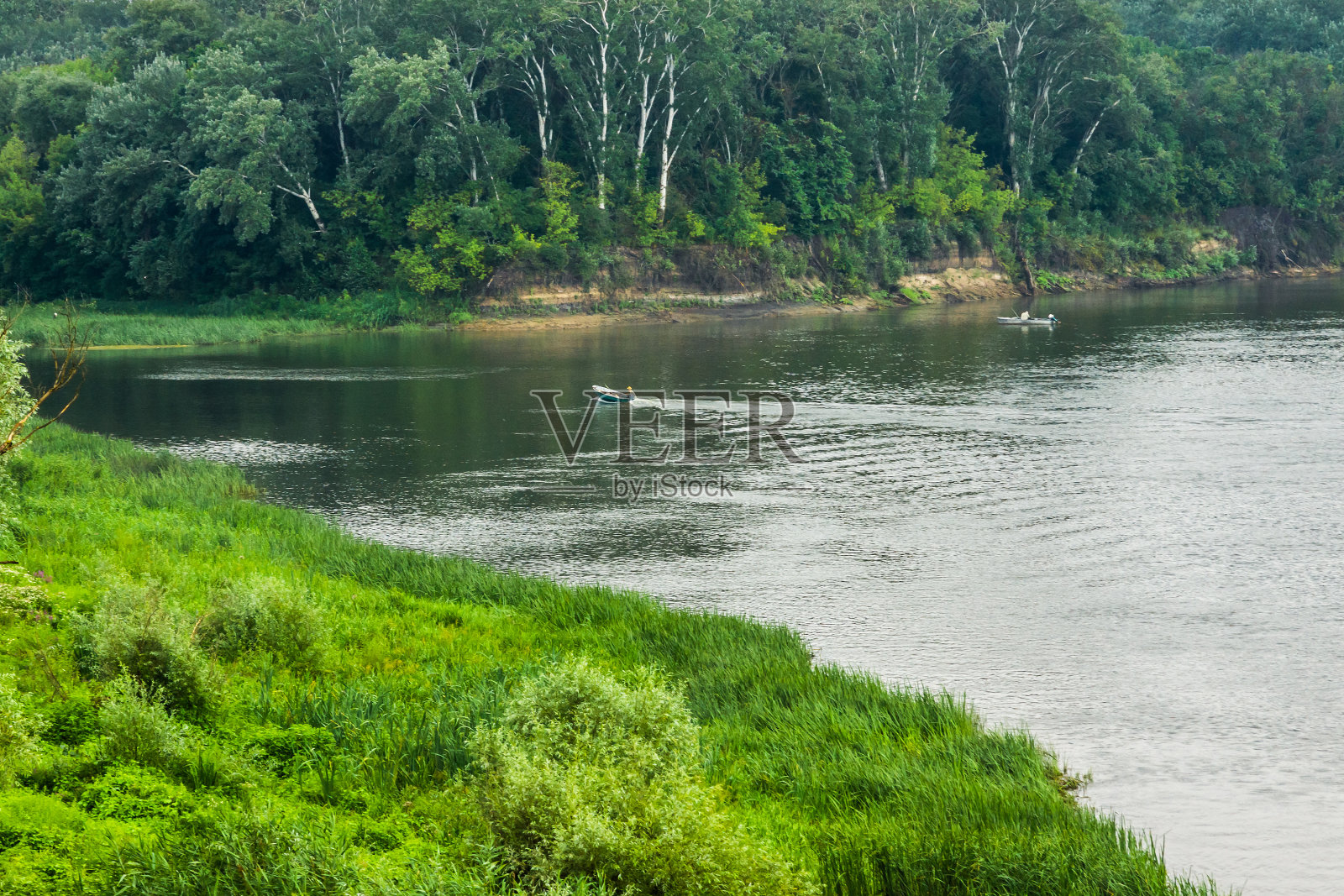河上的渔船在绿色的河岸间照片摄影图片