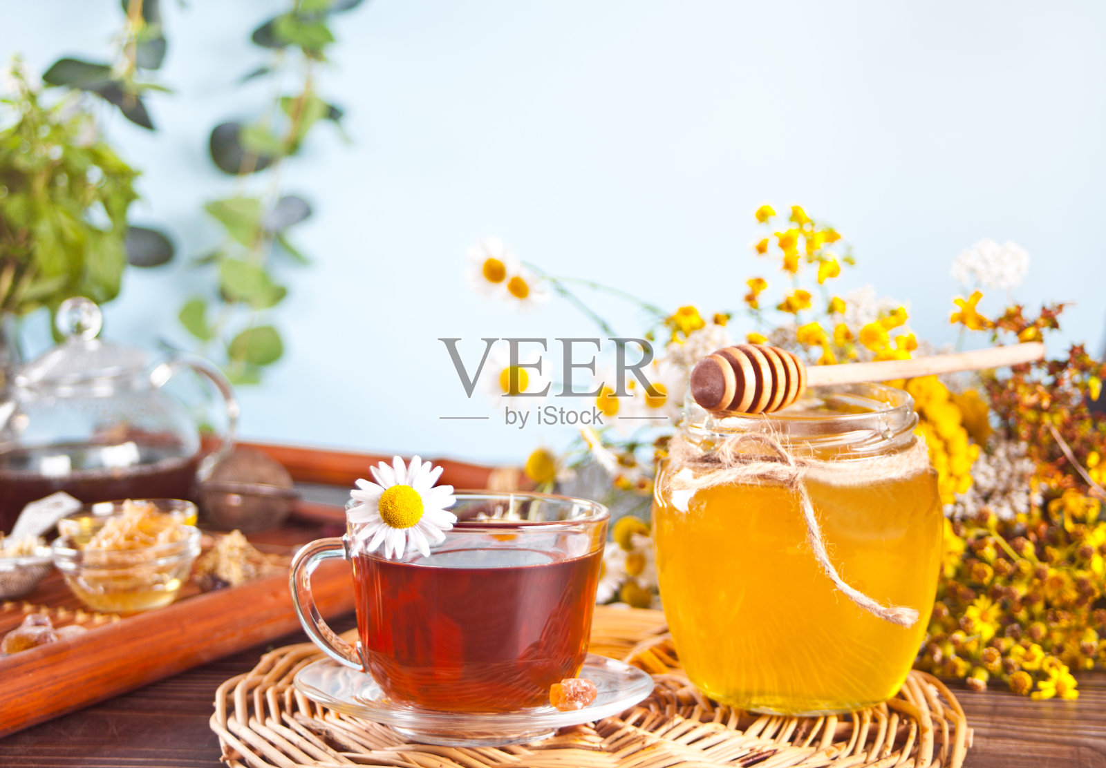 一杯药草甘菊茶,蜂蜜放在罐子里,背景是野花照片摄影图片