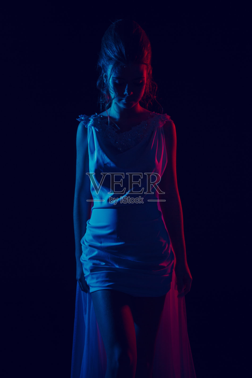 穿着白色连衣裙的年轻优雅女孩的时尚肖像。黑色背景,摄影棚拍摄。照片摄影图片