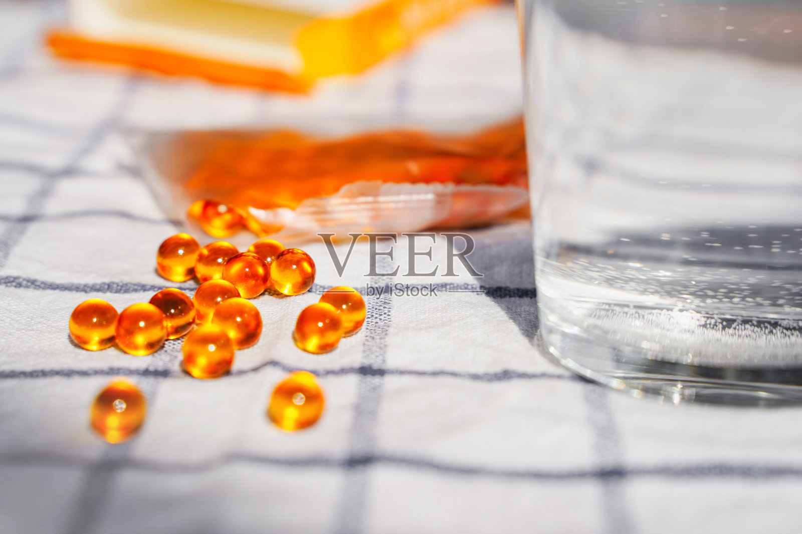 桌上有鱼油胶囊和一杯水。鱼肝油-3。营养补充剂。运动,饮食的概念。照片摄影图片