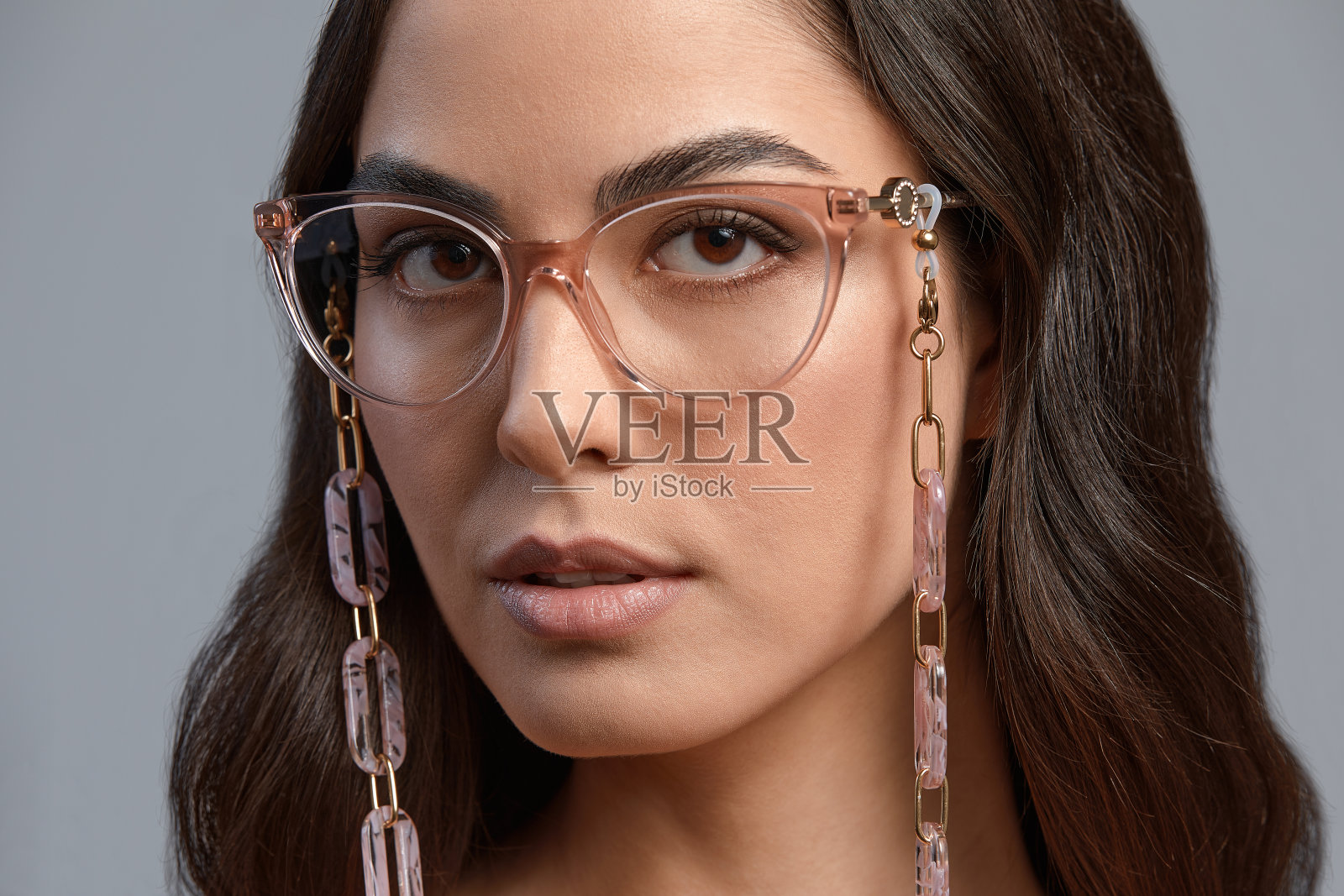 美丽的黑发在灰色的背景上时尚的眼镜,一个女人在眼镜完美的妆,美丽的健康皮肤,灰色的背景,复制空间照片摄影图片