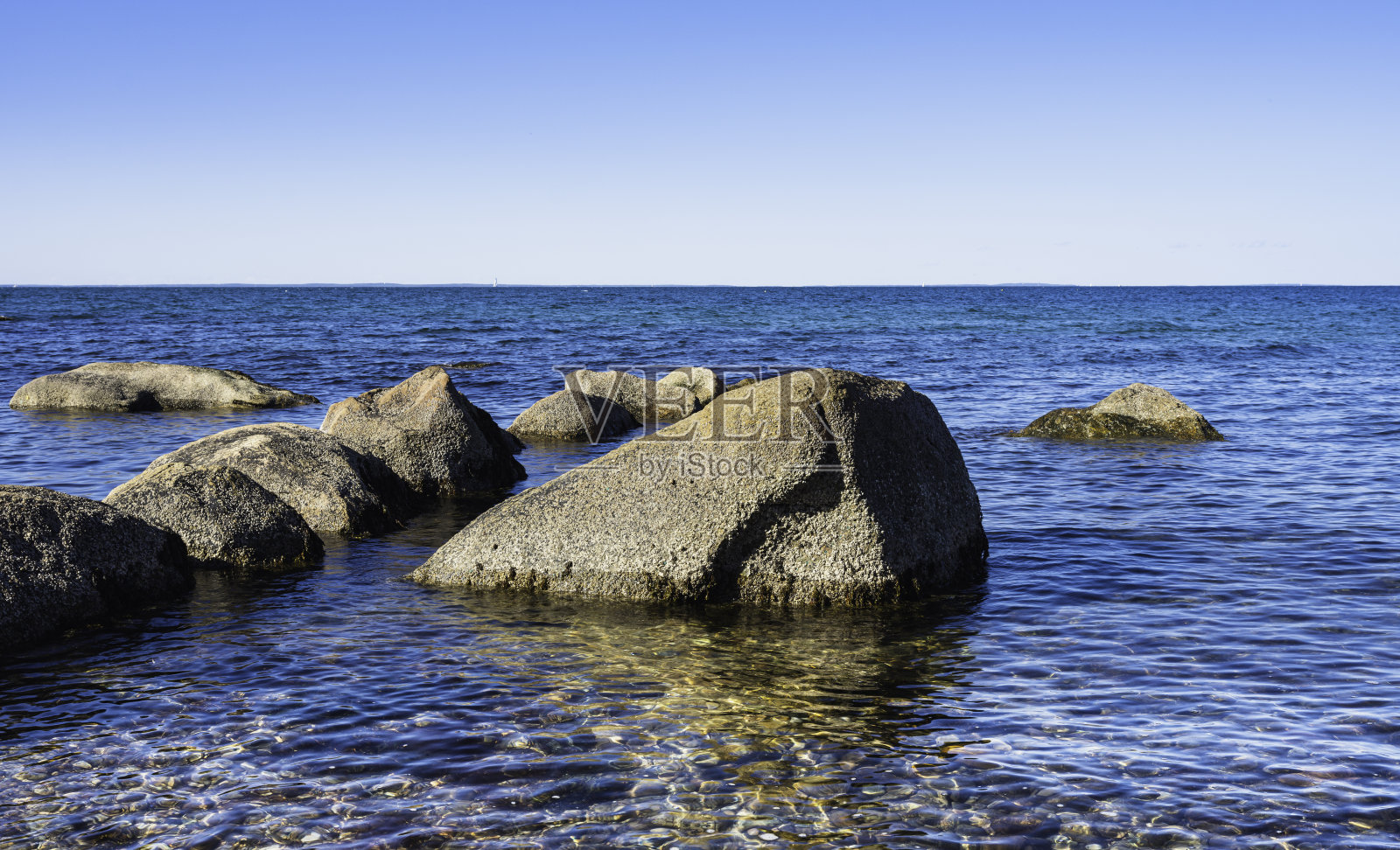 在马萨诸塞州的科德角,清澈的绿松石海水中的冰川岩石的海景。照片摄影图片