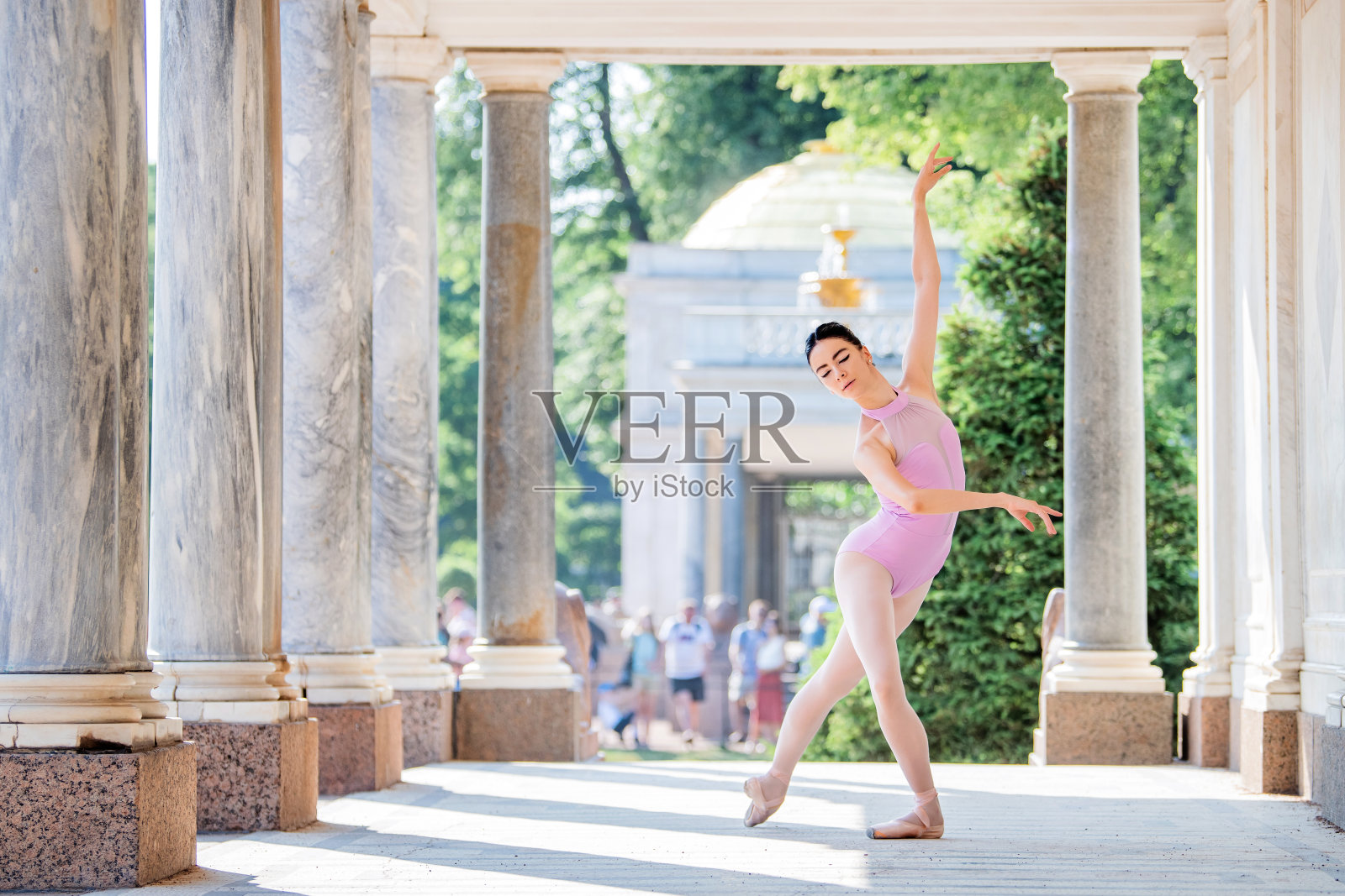 苗条的芭蕾舞女演员穿着尖头鞋,身穿剪影服装,在公园古色古香的建筑背景下跳舞照片摄影图片