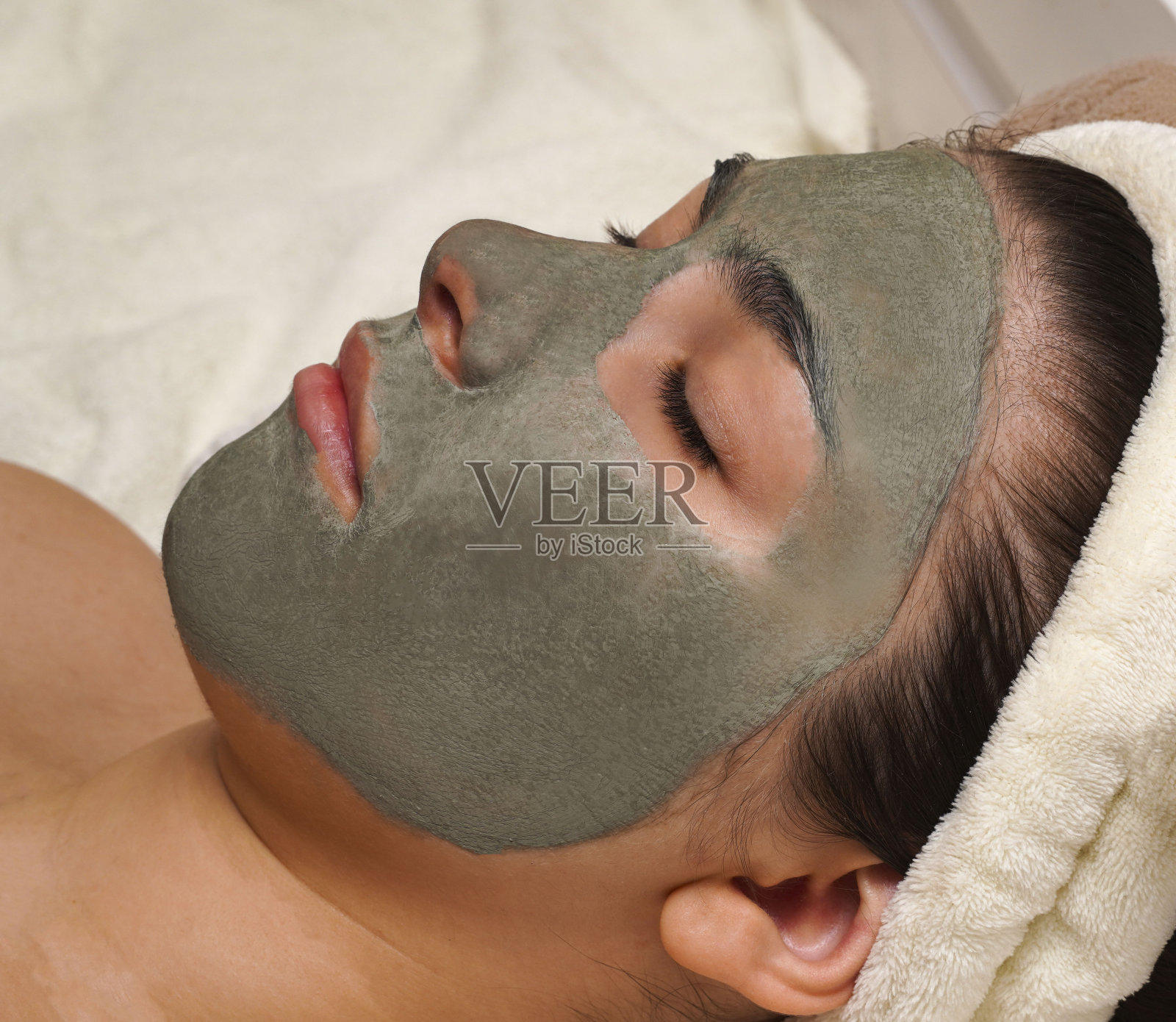 漂亮的年轻女人带着蓝泥化妆面具在家。清洁程序面膜适用于油性痤疮皮肤。皮肤病学的过程。照片摄影图片