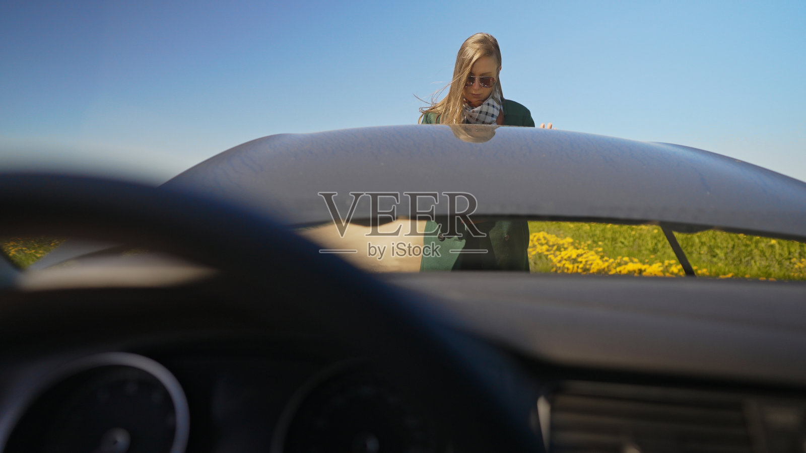 穿着大衣的女人打开了汽车的引擎盖。照片摄影图片