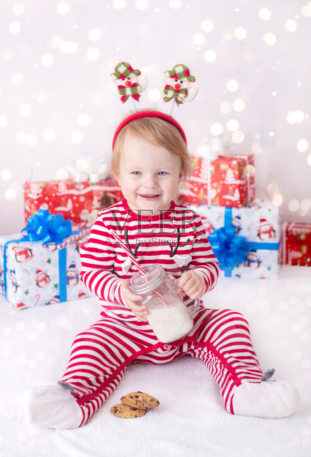 圣诞贺卡小孩子在圣诞老人的帽子里喝牛奶照片摄影图片