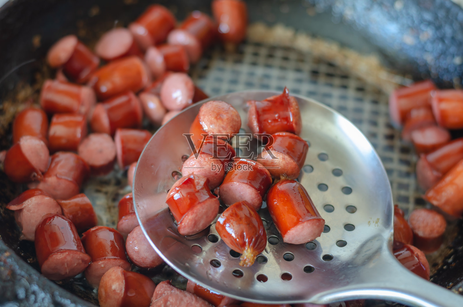 用煎锅煎狩猎香肠。搅拌时开槽照片摄影图片