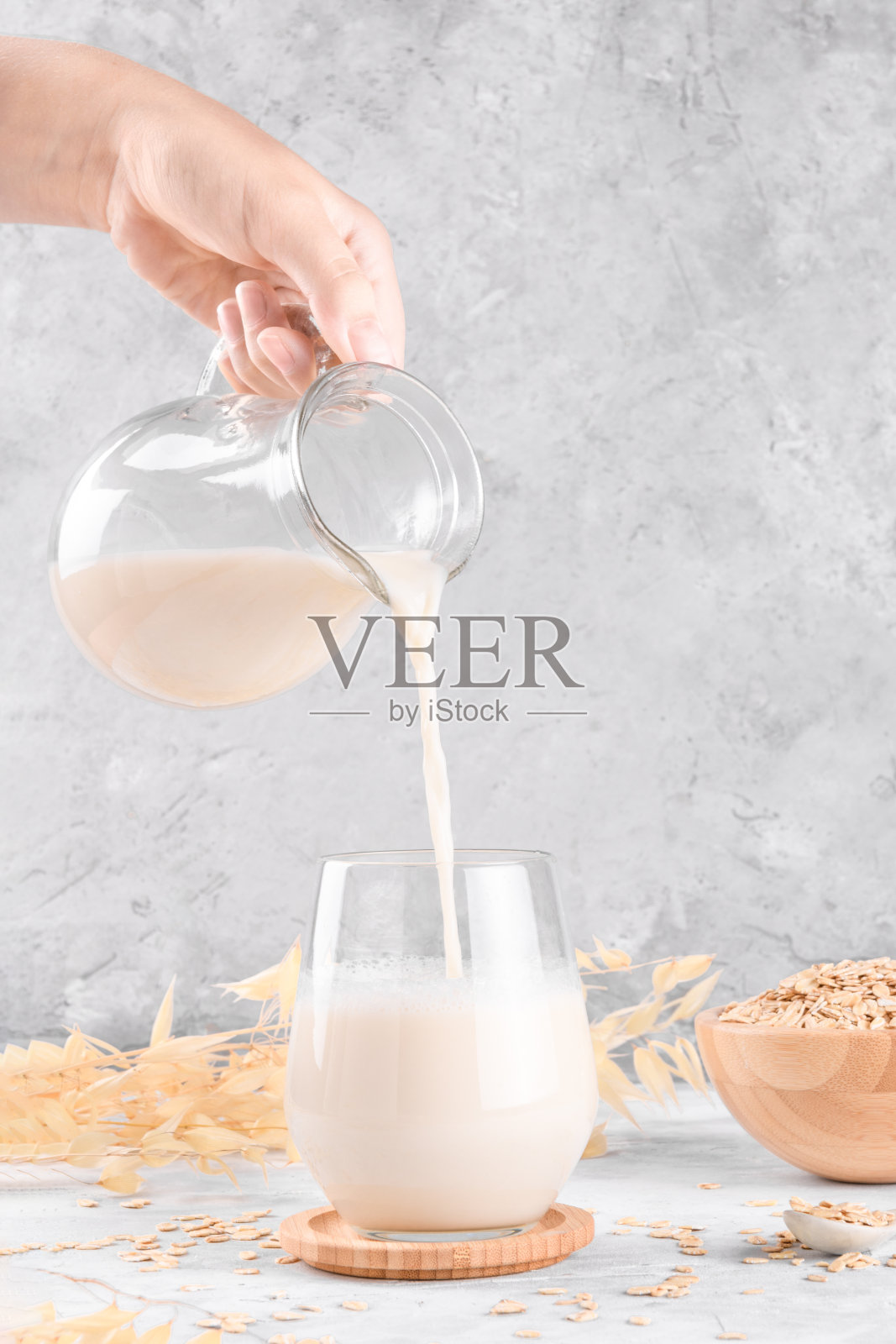 一位女士正将牛奶从罐子里倒入玻璃杯中照片摄影图片