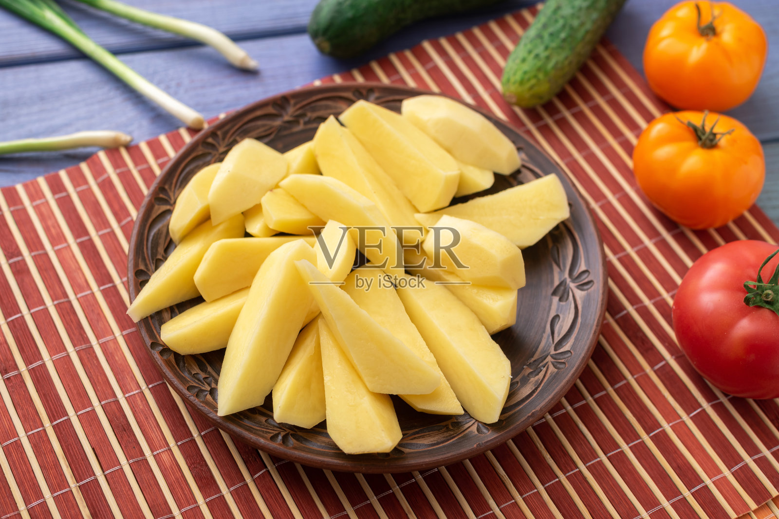 生的去皮切土豆块茎放在厨房桌子上的盘子和蔬菜。准备做饭。照片摄影图片