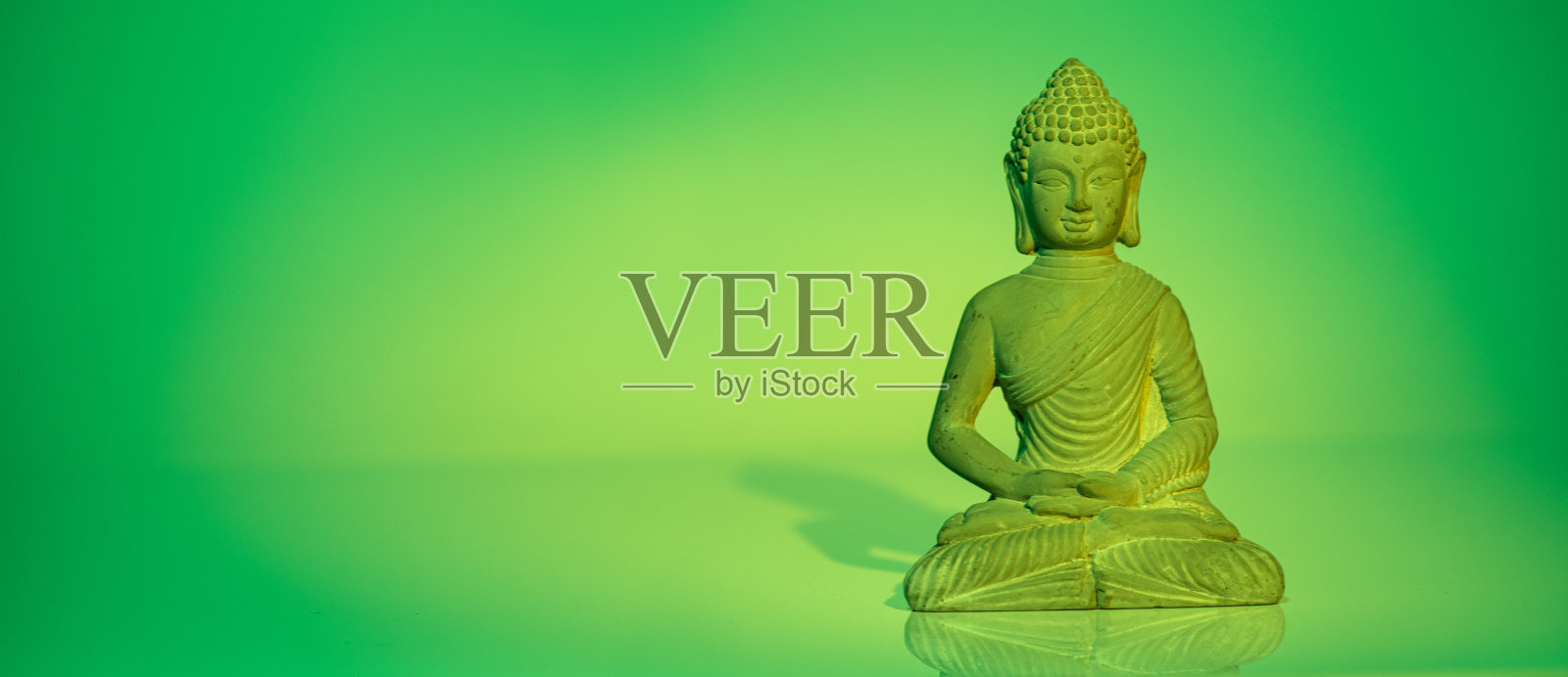 绿色照明石佛像压克力地下在一个绿色照明背景前面照片摄影图片