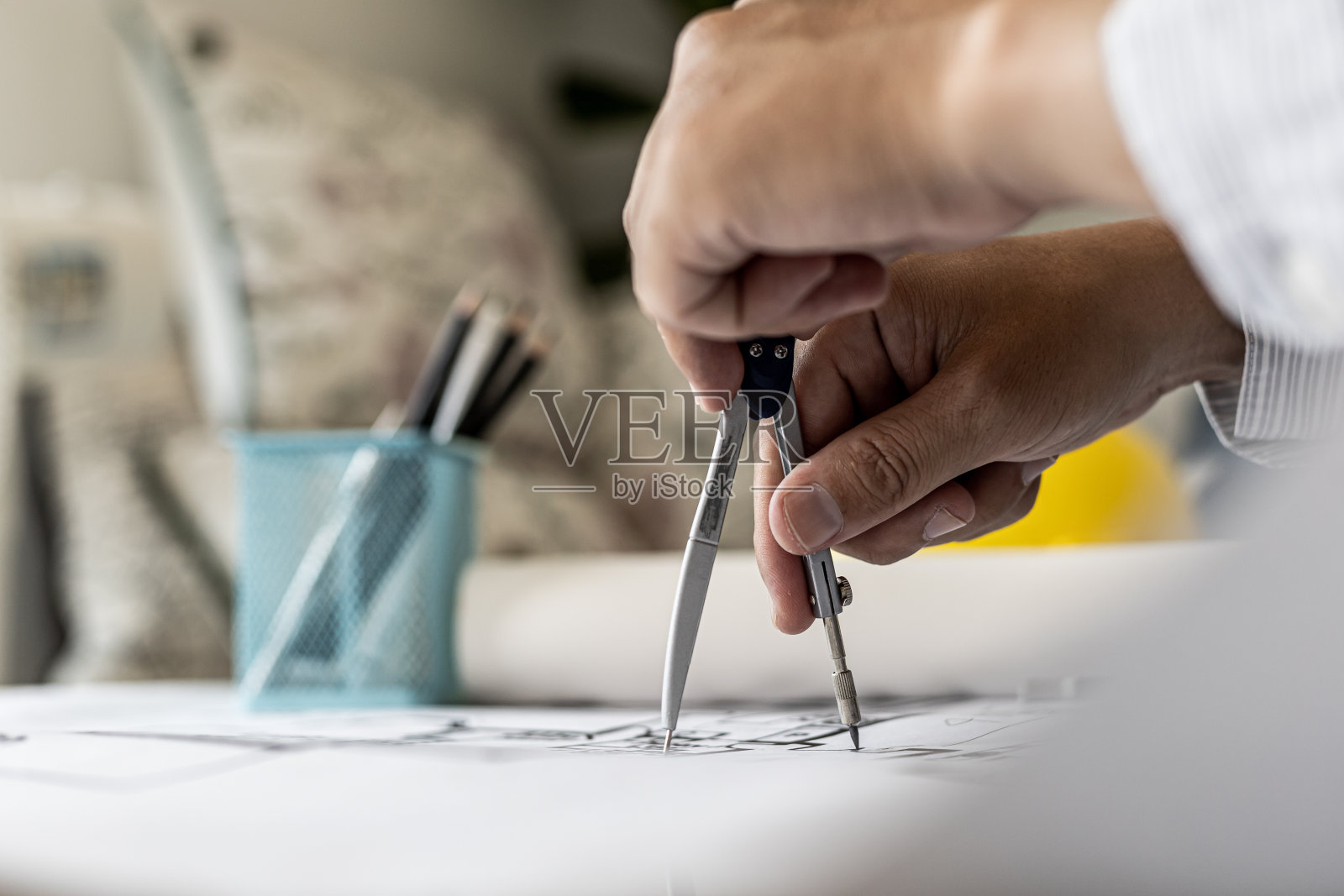 建筑师使用圆规在房屋蓝图上书写,按照标准和法律进行建筑设计,根据居民的需要进行建筑设计。照片摄影图片