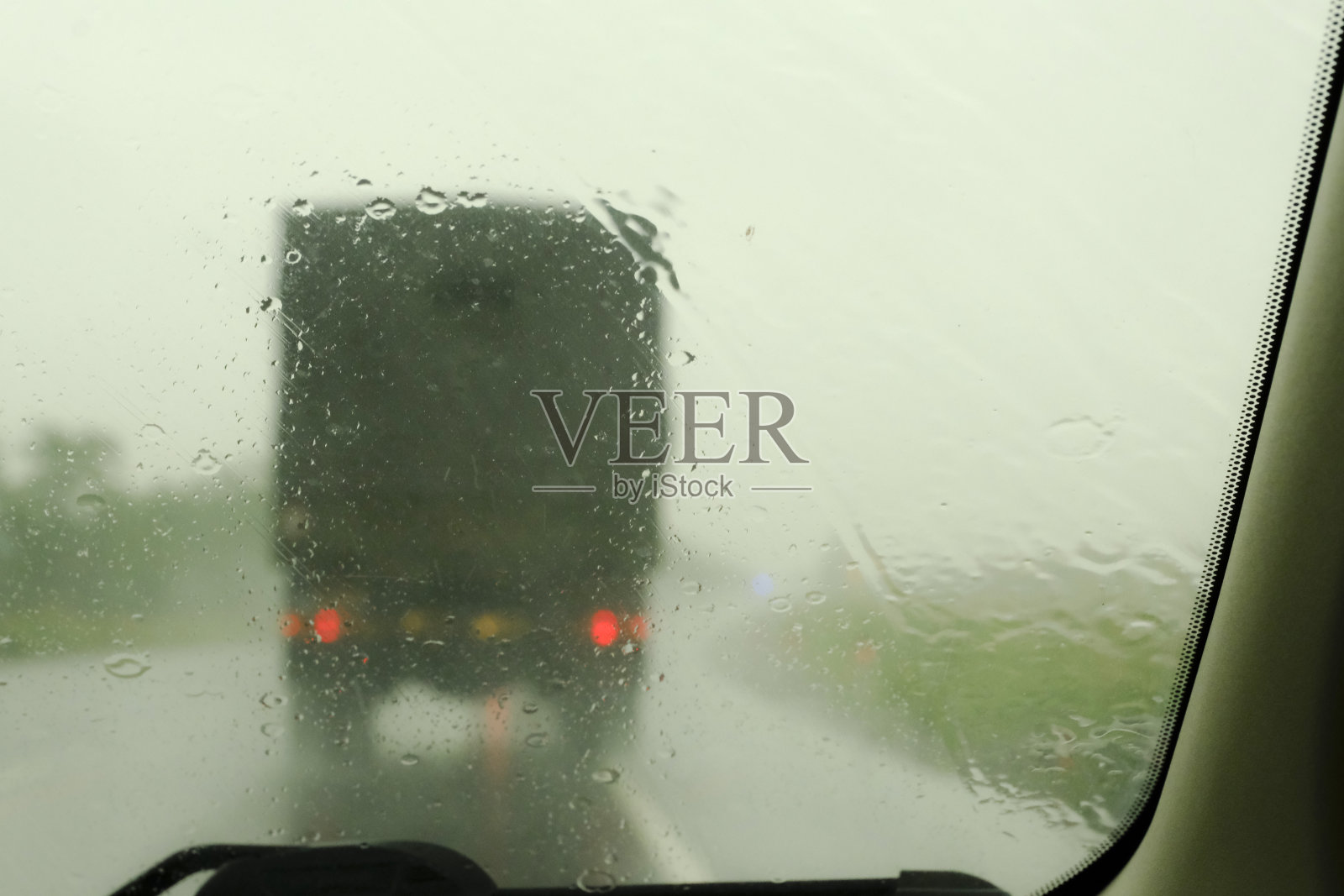 高速公路上的一列现代化军车。通过被雨覆盖的汽车挡风玻璃看到的散焦交通这是在秋天照片摄影图片