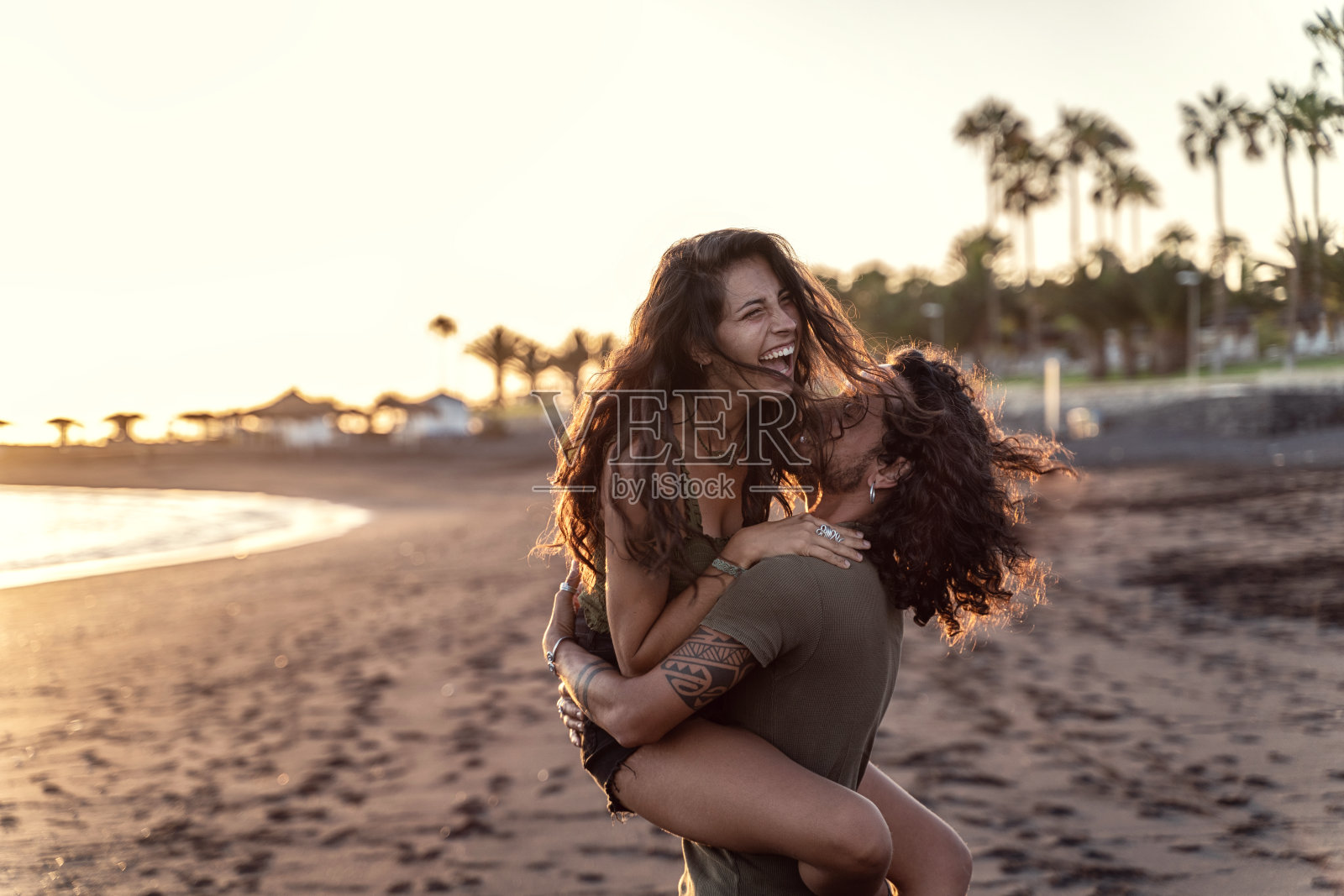 幸福美丽的意大利夫妇一起在海滩上玩,笑。日落时间。照片摄影图片