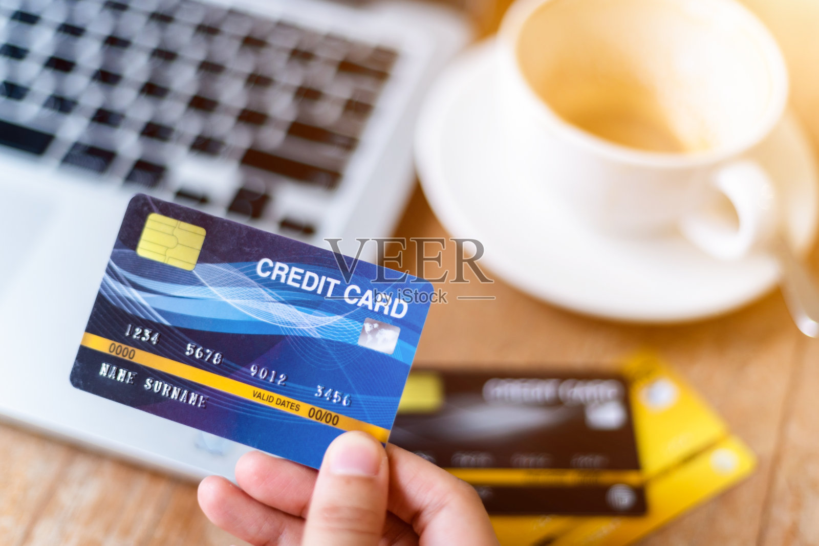 特写的自由职业者商业女性手握信用卡休闲工作使用笔记本电脑与咖啡杯在咖啡馆的背景,在线支付购物的概念照片摄影图片