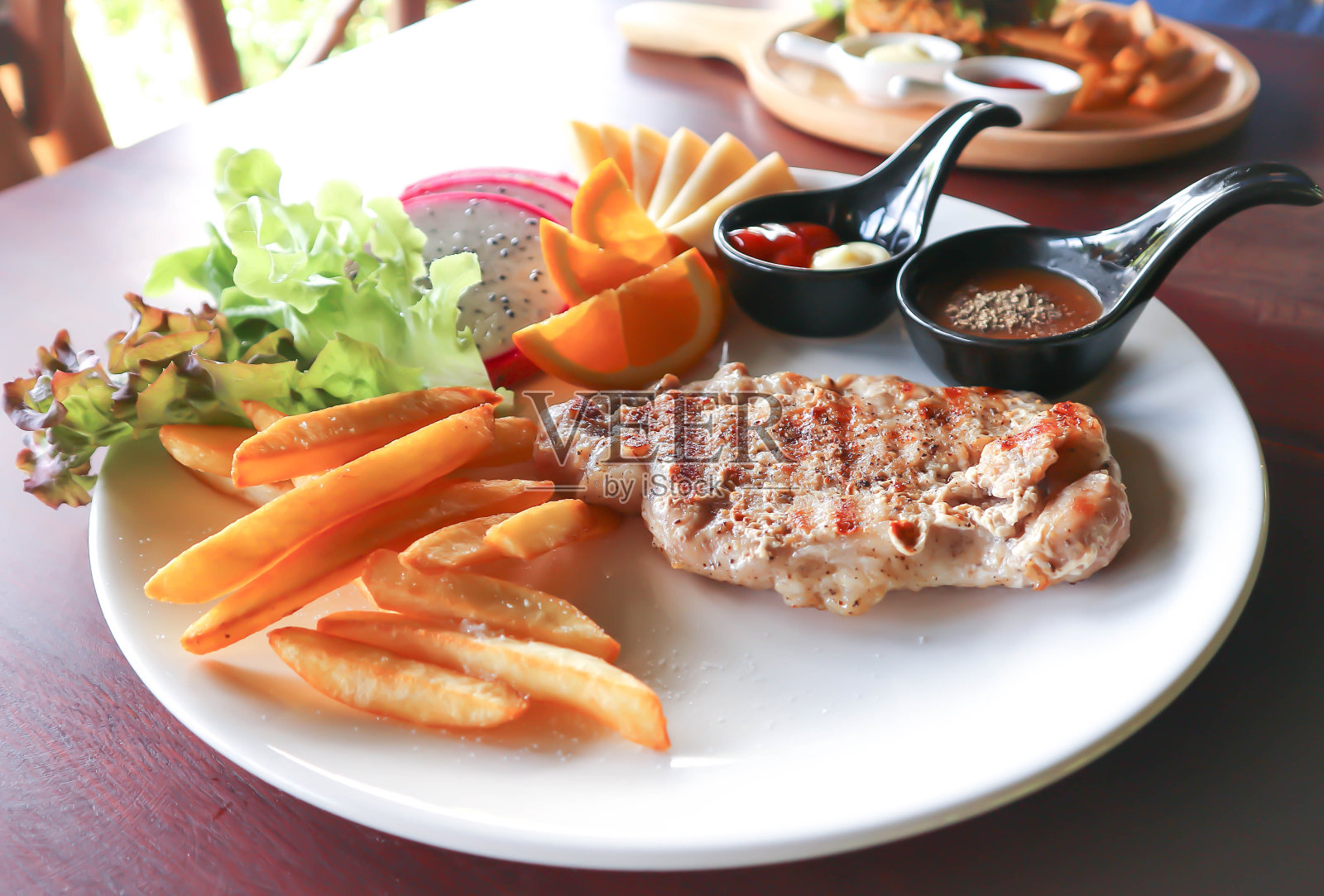 烤猪肉,牛排配薯条和水果照片摄影图片