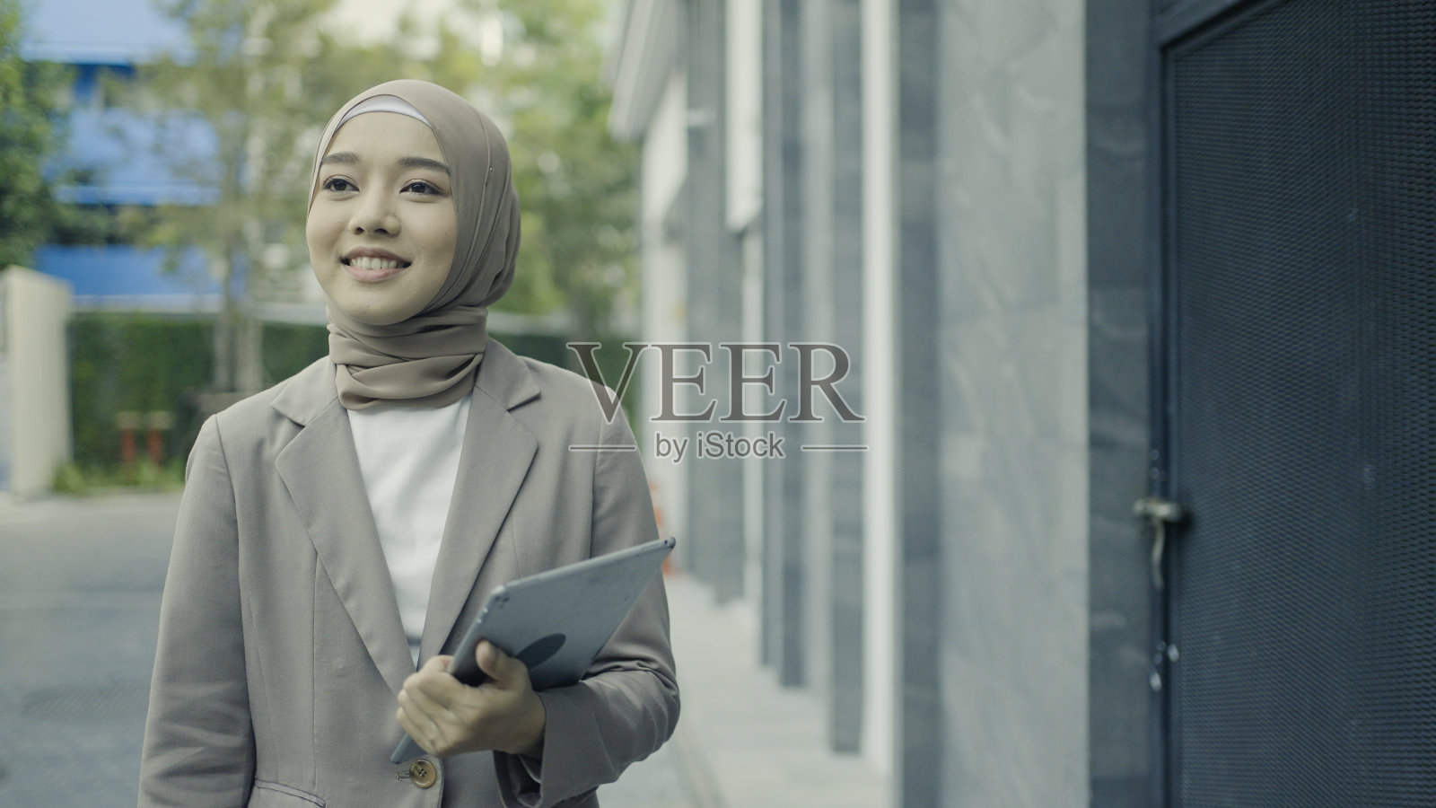 女商人走在校园,手里拿着电子平板电脑照片摄影图片