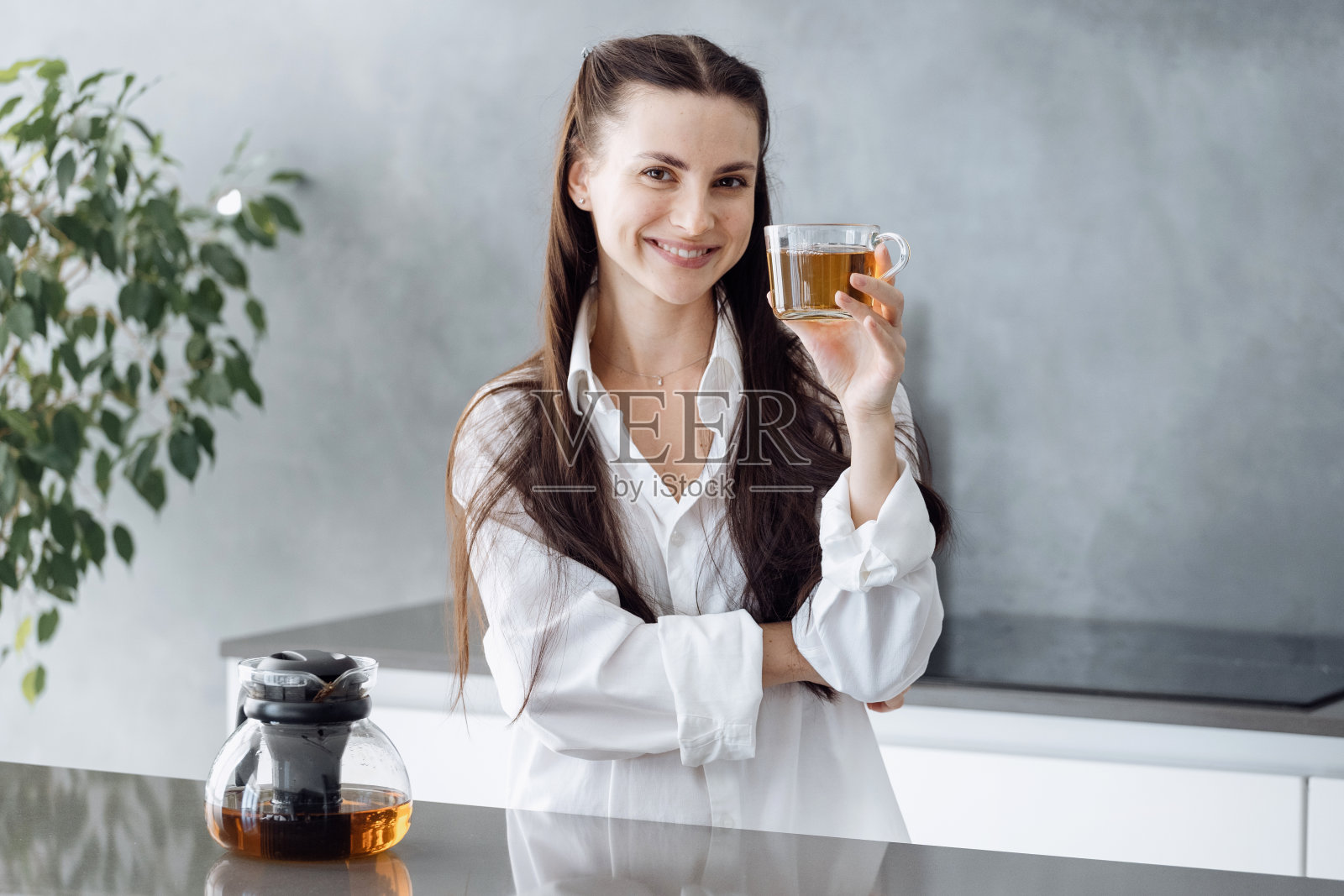 快乐的女人站在台面后喝茶照片摄影图片