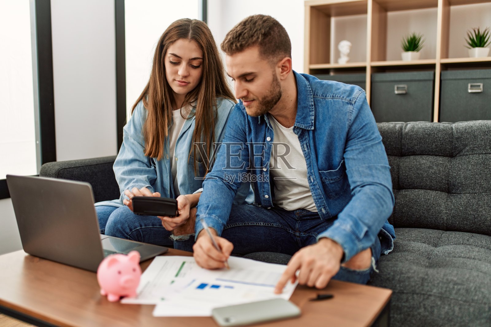 年轻的白人夫妇控制着家里的经济。照片摄影图片