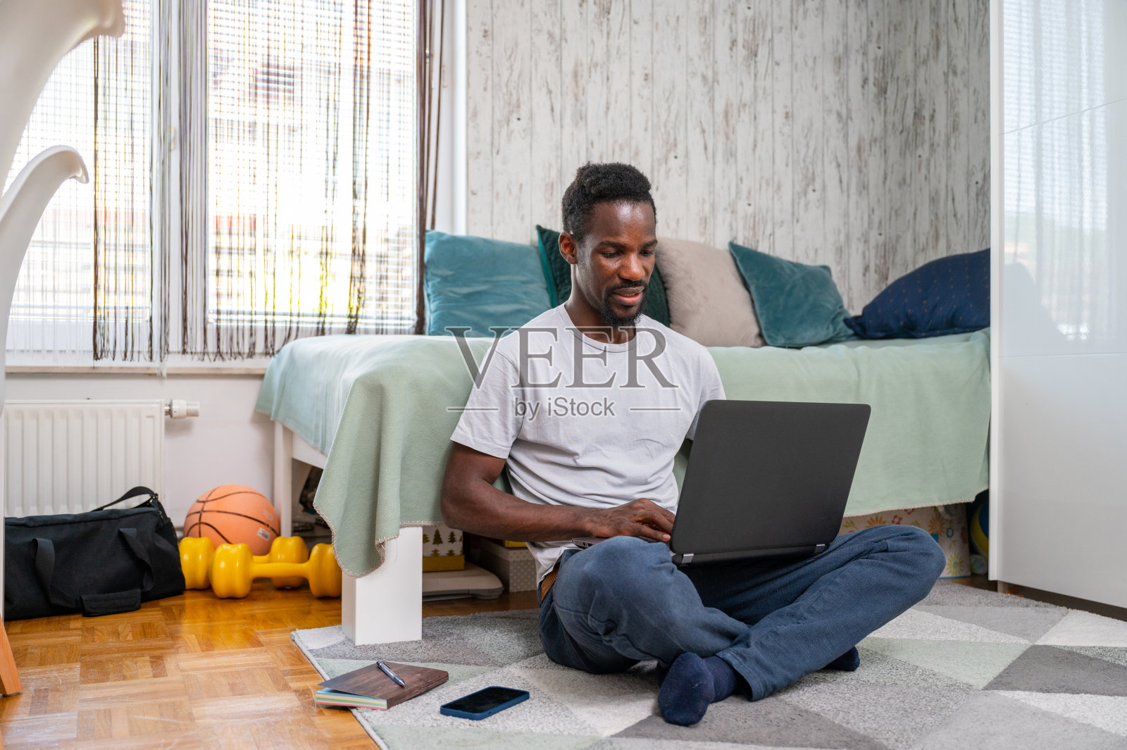 一个年轻人坐在地板上用笔记本电脑照片摄影图片