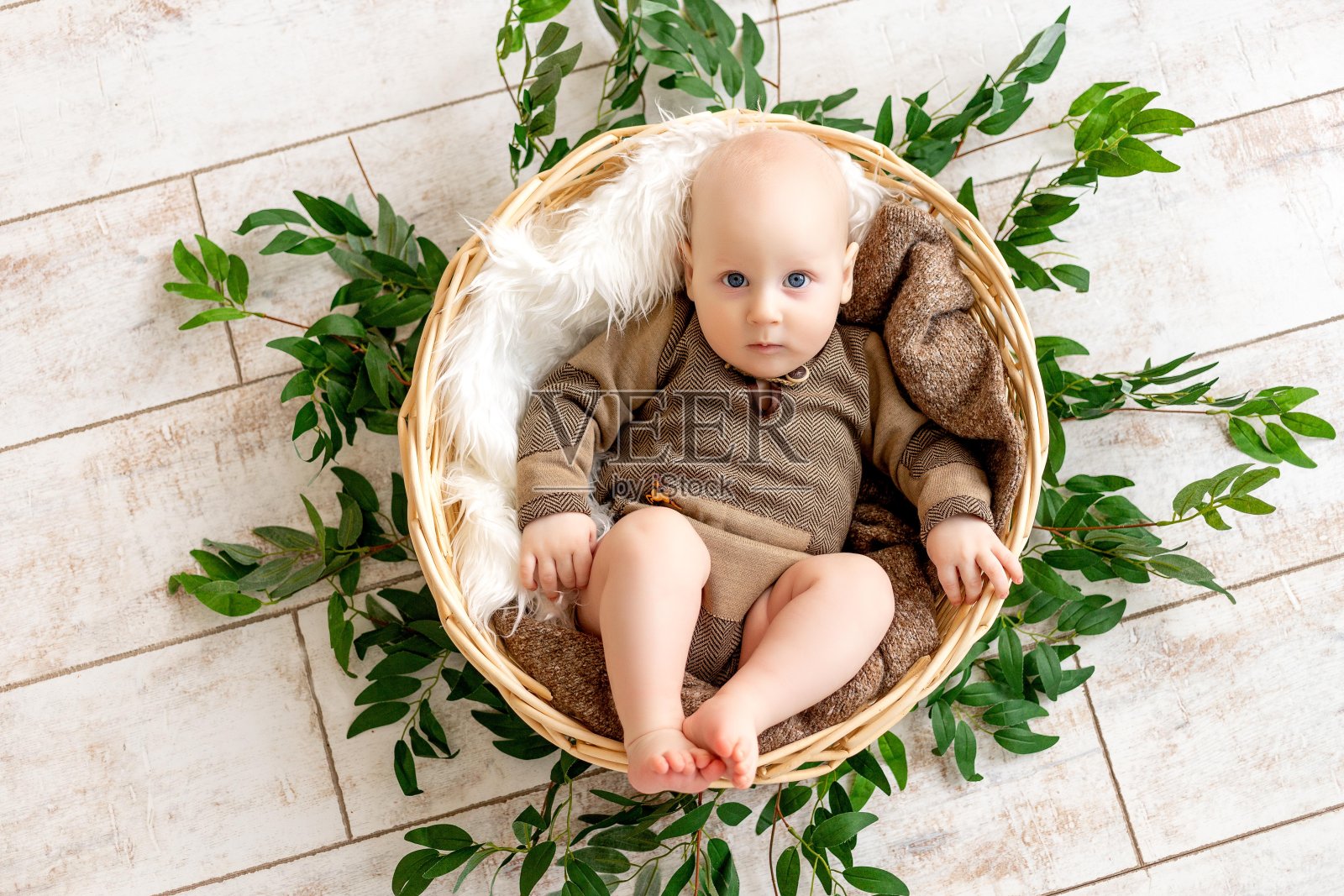 一个小男孩躺在篮子里,看着镜头照片摄影图片