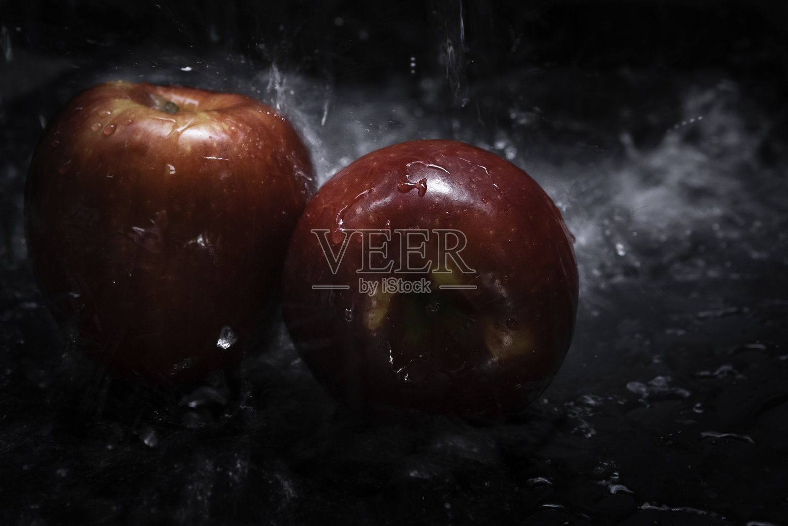 新鲜的红苹果放在淡水中,黑色背景。照片摄影图片