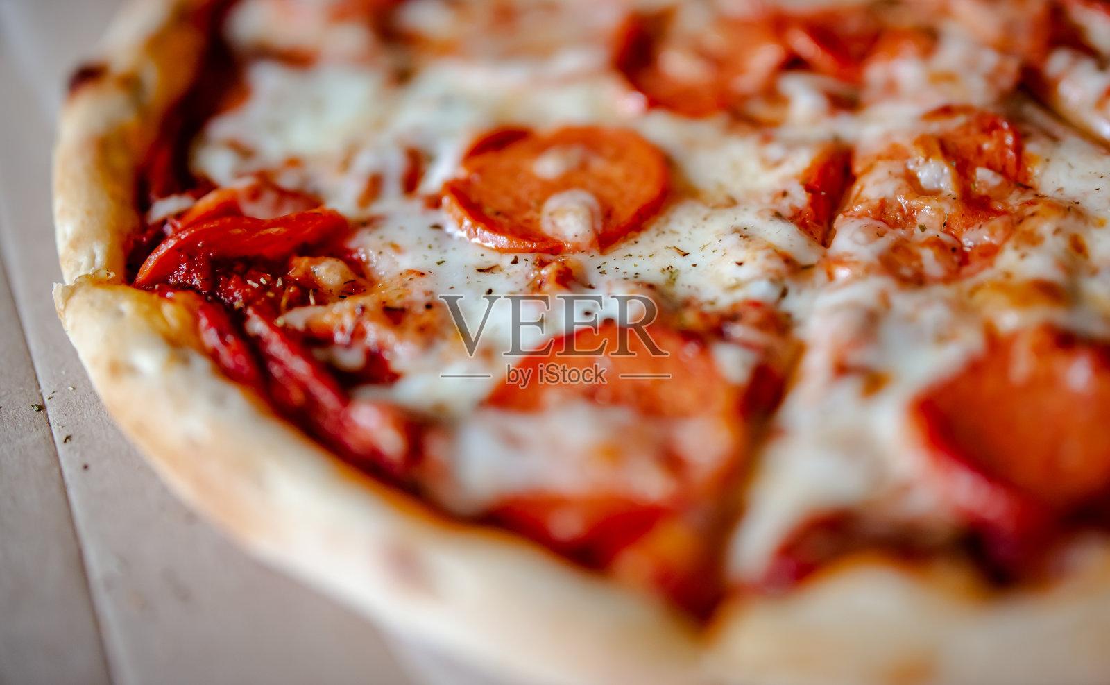 意大利辣香肠披萨配马苏里拉芝士,意大利腊肠,番茄酱,胡椒,香料照片摄影图片