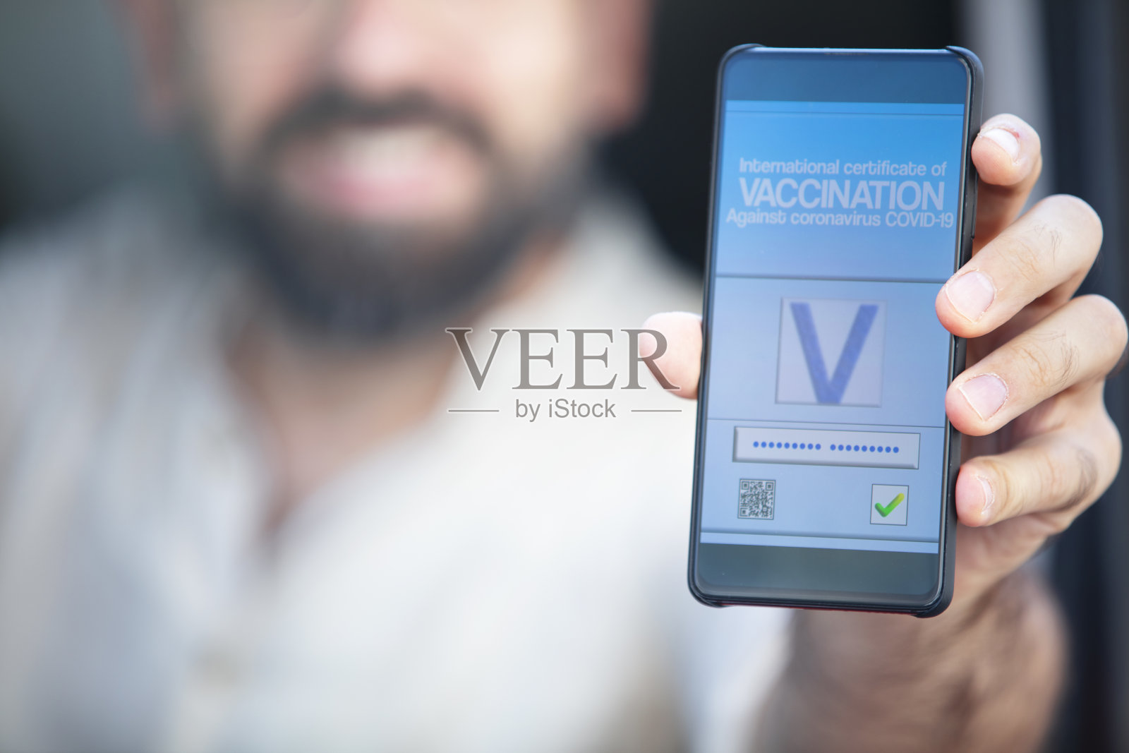 智能手机上显示的是陌生男性手中的有效疫苗接种证书照片摄影图片